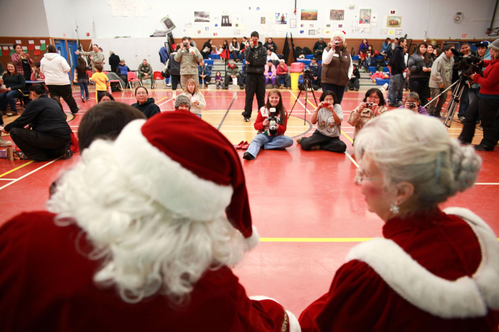 Santa and Mrs. Claus pose for photographs with residents of all ages to preserve the memories made. The village of around 185 residents welcomed the volunteers into their school for the day to celebrate Christmas.  (Alaska National Guard photo\Lt. Bernie Kale),

