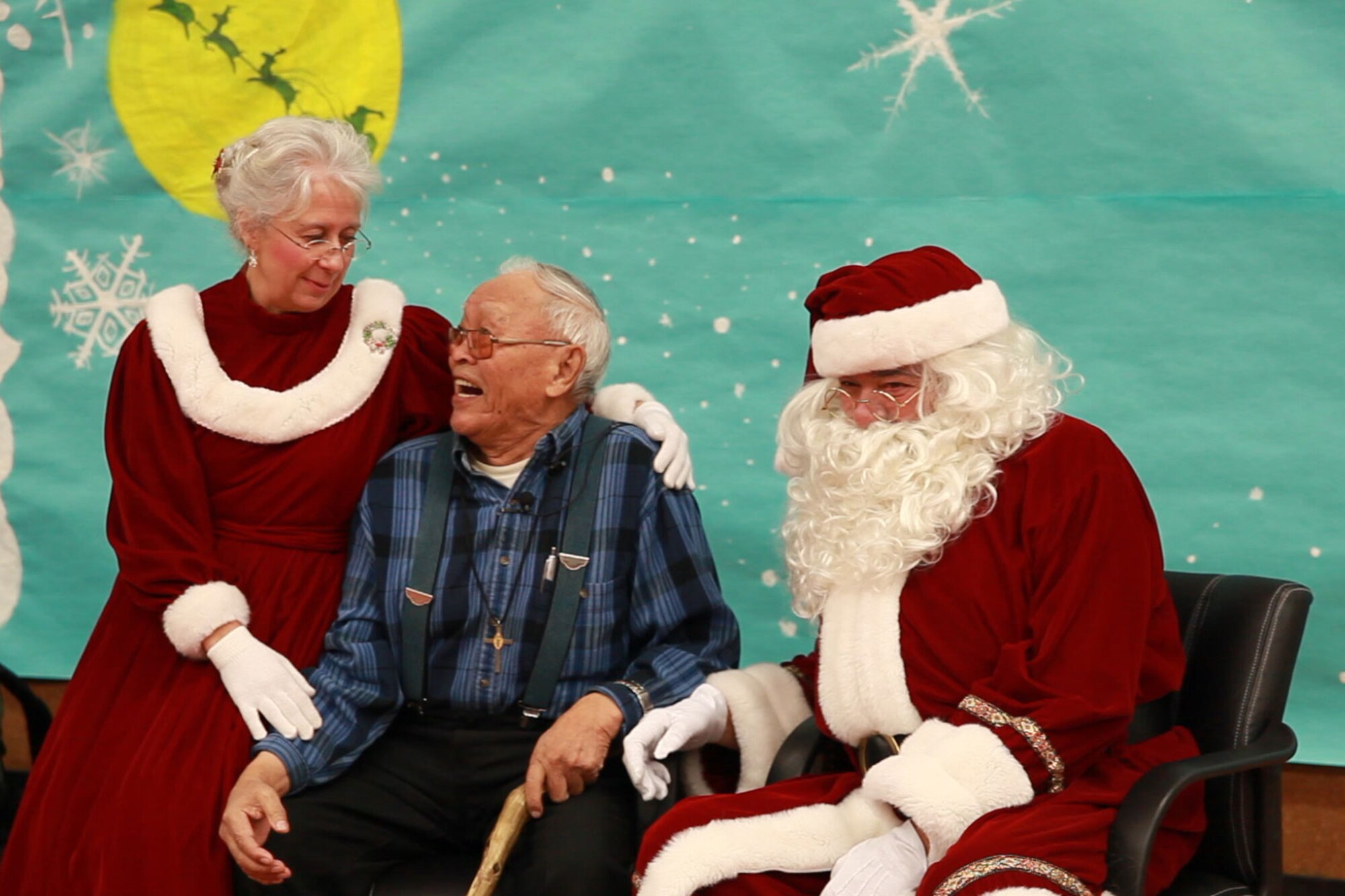 Johnson Moses, 87, poses for a picture with Santa and Mrs. Claus during the celebration. Moses is one of the village elders in Allakaket who welcomed the volunteers into his village. (Alaska National Guard photo\Lt. Bernie Kale),
