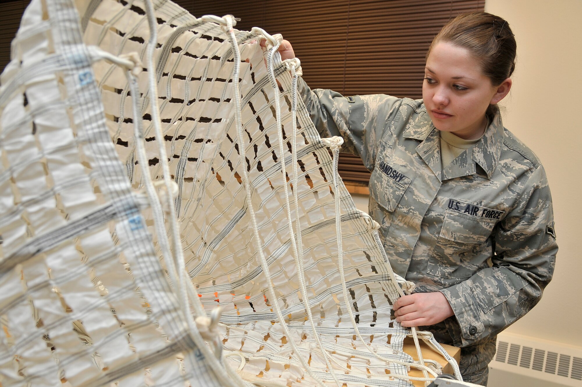 U.S. Air Force Airman Lauren Handshy inspects an F-16 drogue chute for rips, tears and deterioration Nov. 28, 2011, Eielson Air Force Base, Alaska. The chute slows and steadies aircraft ejection seats during high speed ejections. Handshy is an aircrew flight equipment apprentice assigned to the 354th Operation Support Squadron. (Photo by Jayde Patterson/Released)