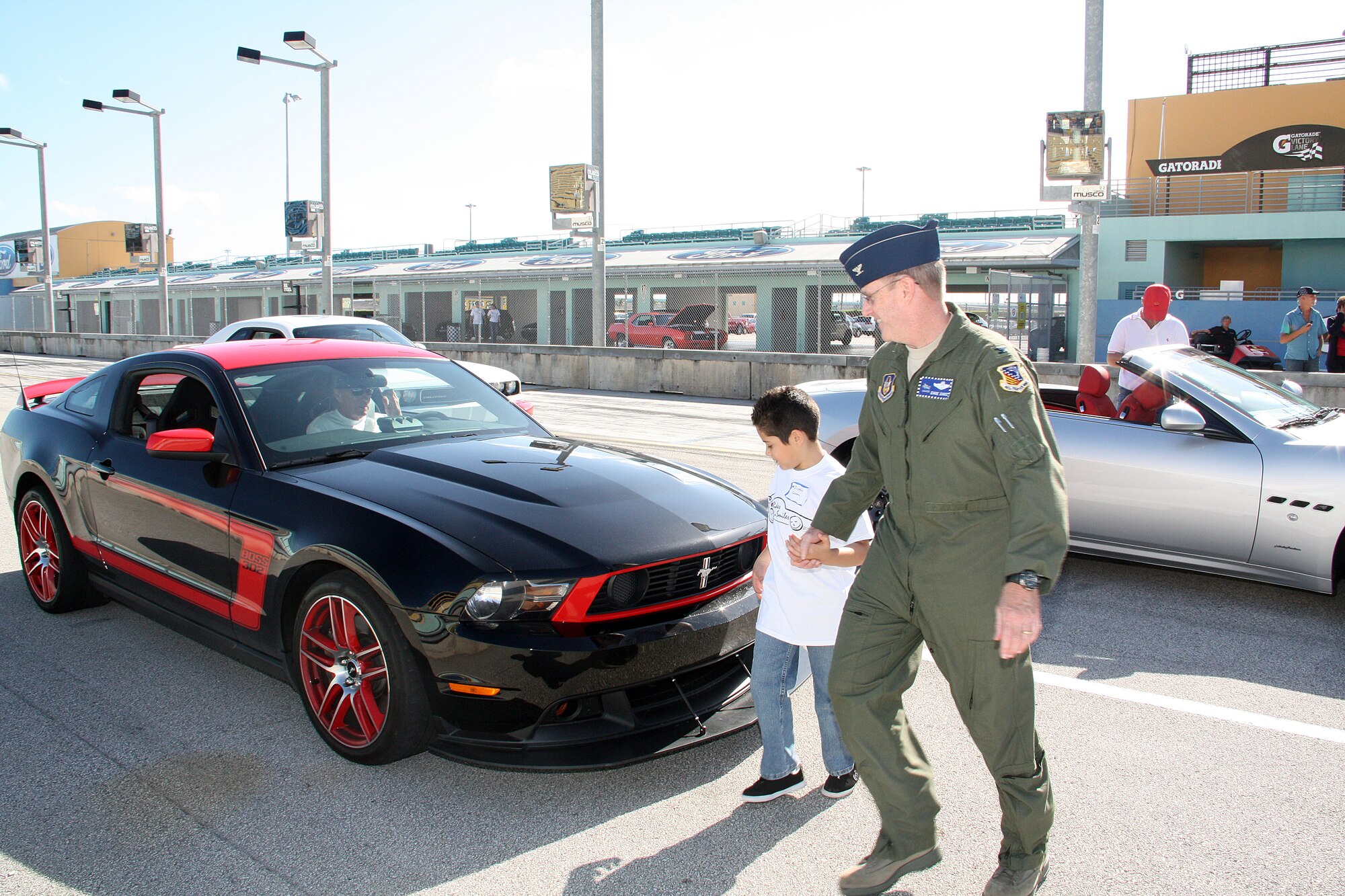 Col. David Davis, 482nd Fighter Wing vice commander escorts a child to a high performance Boss 302 Mustang for a thrilling ride during the Fourth Annual Rides-N-Smiles Track Day at Homestead-Miami Speedway Nov. 26.