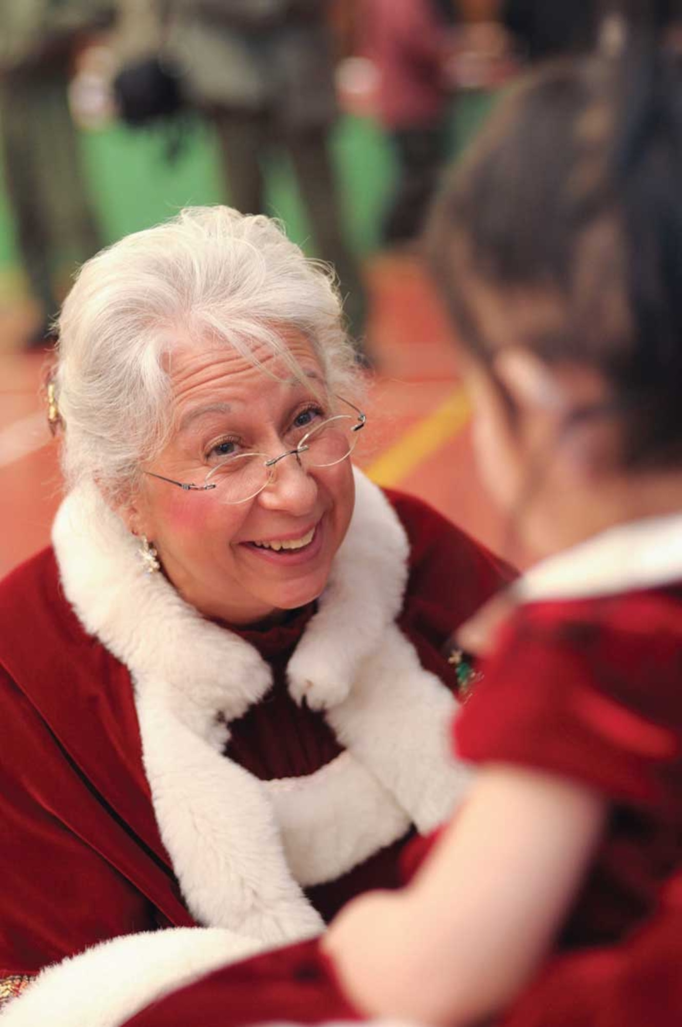Mrs. Claus kneels down in front of a four-year-old Allakaket resident. The village of 185 residents welcomed the volunteers into their school for the day to celebrate Christmas. (Alaska National Guard photo/1st. Lt. Bernie Kale)