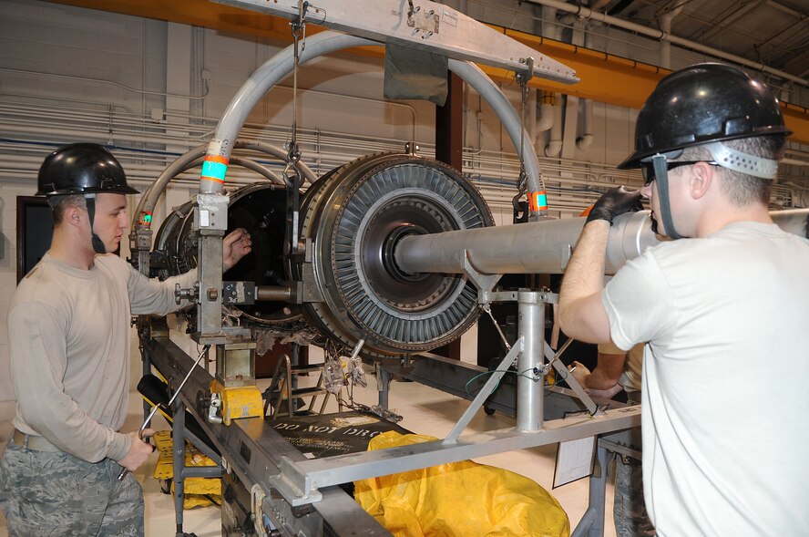 Airmen 1st Class Daniel White and Troy Kingery, 4th Component Maintenance Squadron jet engine mechanics, remove a component from an F100-220E engine at Seymour Johnson Air Force Base, N.C., Nov. 29, 2011. Airmen at the jet engine mechanic back-shop are the first stop for jet engines. When the engines are delivered from the flightline, these Airmen assess the engine, determine the problem and send it to the modular repair shop to have it repaired. White hails from Niceville, Fla., and Kingery hails from Toledo, Ill. (U.S. Air Force photo by Senior Airman Gino Reyes)