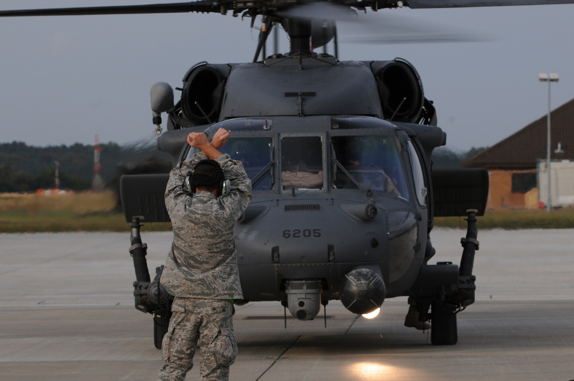ROYAL AIR FORCE LAKENHEATH, England - A crew chief from the 748th Aircraft Maintenance Squadron marshalls in a HH-60 Pave Hawk after returning from several deployments, September 15, 2011. Approximately 60 members from the 56th Rescue Squadron returned home after back-to-back deployments lasting more than nine months in support of Operations Enduring Freedom, Odyssey Dawn and Unified Protector.  The 56th RQS  is a combat-ready search and rescue squadron of HH-60G Pave Hawk helicopters capable of executing all-weather search and rescue missions day or night in hostile environments in support of the United States and its allies. (U.S. Air Force photo by Airman Cory D. Payne)