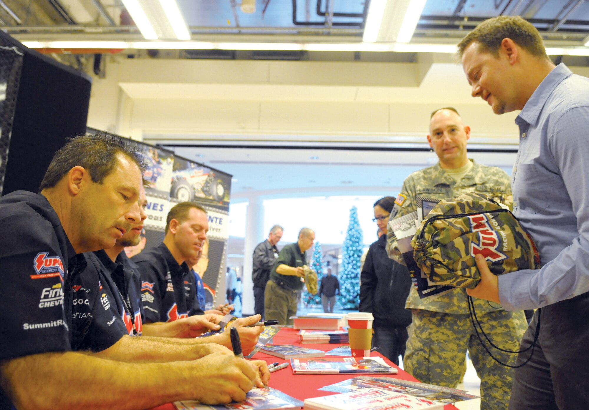 Greg Anderson, a four time National Hot Rod Association Pro Comp drag racing Champion, autographs a photo for a fan inside the Kaiserslautern Military Community Center here, Nov. 23, 2011 . Anderson along with three other NHRA members came to Germany to visit troops and say thank you. This is the seventh time members of the NHRA have toured Germany in honor of the troops. (U.S. Air Force Photo by Staff Sgt. Travis Edwards)
