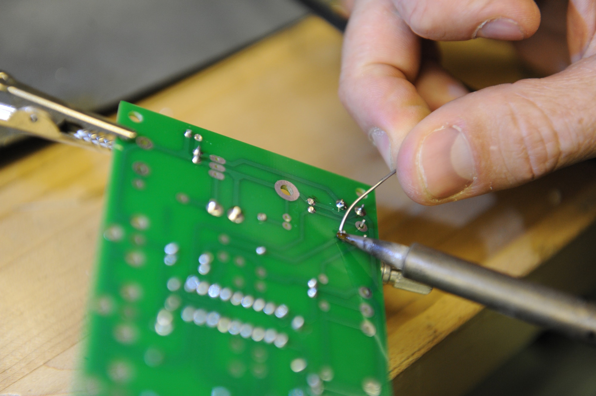 Army Staff Sgt. Jeremy Hedlind solders a component onto a printed circuit board while repairing a television set, Oct. 4, 2011. Hedlind and his group of electronics specialists have started a volunteer shop to repair personal electronics for the deployed Airmen, Soldiers and Sailors at the 380th Air Expeditionary Wing, lending their time and talents to help other service members, while gaining valuable experience and honing their skills. Hedlind is the missile maintenance NCO for the intermediate support element of the 3rd Battalion, 4th Air Defense Artillery Regiment and is deployed from Fort Bragg, N.C. He hails from Eugene, Ore. (U.S. Air Force photo/Master Sgt. Chance Babin) 