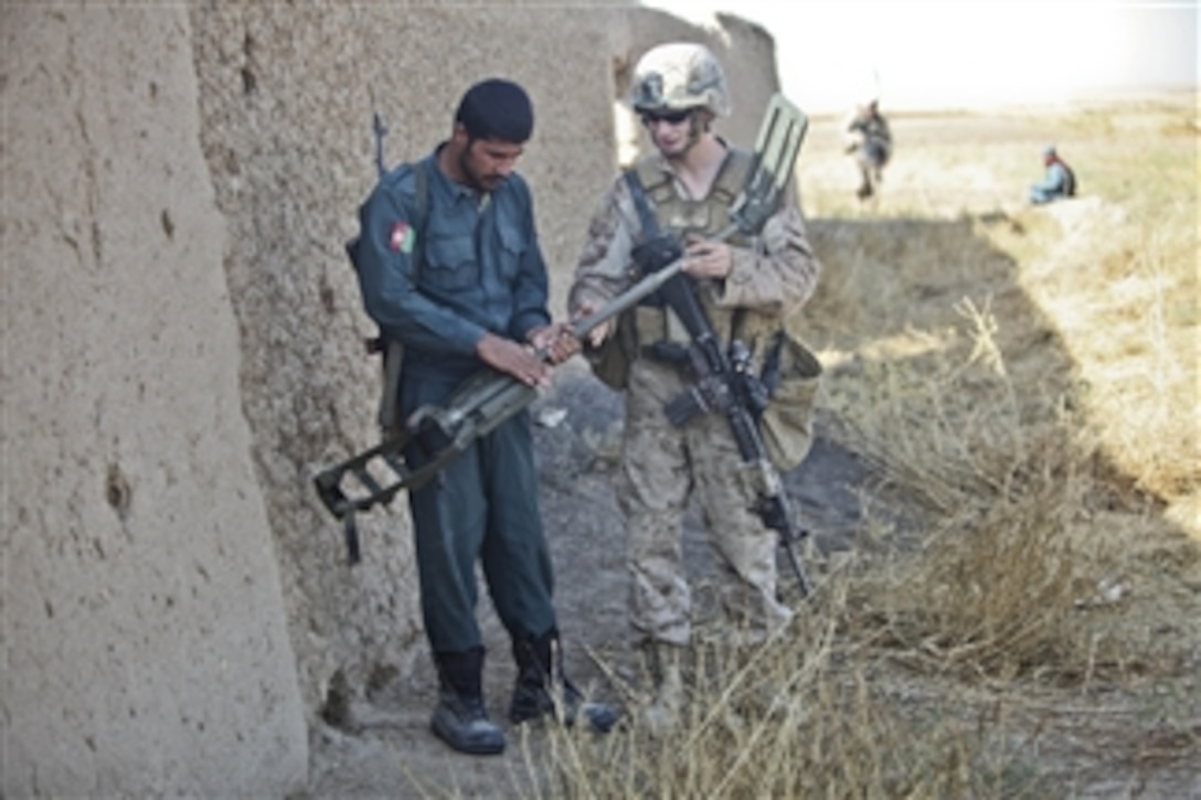 U.S. Marine Corps Lance Cpl. Lance Souders with 1st Battalion, 9th Marines shows an Afghan police officer how to use a metal detector while conducting a partnered patrol around the precinct Faslodeen, Nawa, Helmand province, Afghanistan, on Nov. 18, 2011.  The Afghan police conducted patrols and employed counter improvised explosive device measures in order to take the lead in providing security in Nawa district.  