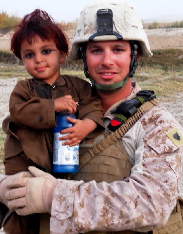 Sgt. Michael J. Favata Jr., platoon guide, 2nd Platoon, Alpha Company, 9th Engineer Support Battalion, 1st Marine Logistics Group (Forward), holds a young Afghan girl in Helmand province, Afghanistan. Favata has helped with the construction of structures that offer increased protection and mobility for deployed Marines such as indirect fire bunkers, blast mitigation pits, land bridges, and entry control points.