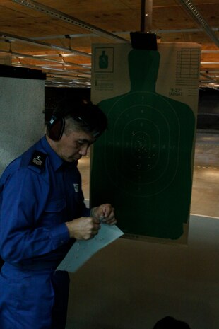 Japanese Maritime Self-Defense Force Petty Officer 1st Class Hiroshi Nagashima, a Fleet Air Wing 31 air crewman, posts a fresh target for the next shooter during rifle re-qualification and familiarization training at the Indoor Small Arms Range here Dec. 2. The sailors shot in groups of six at a time.