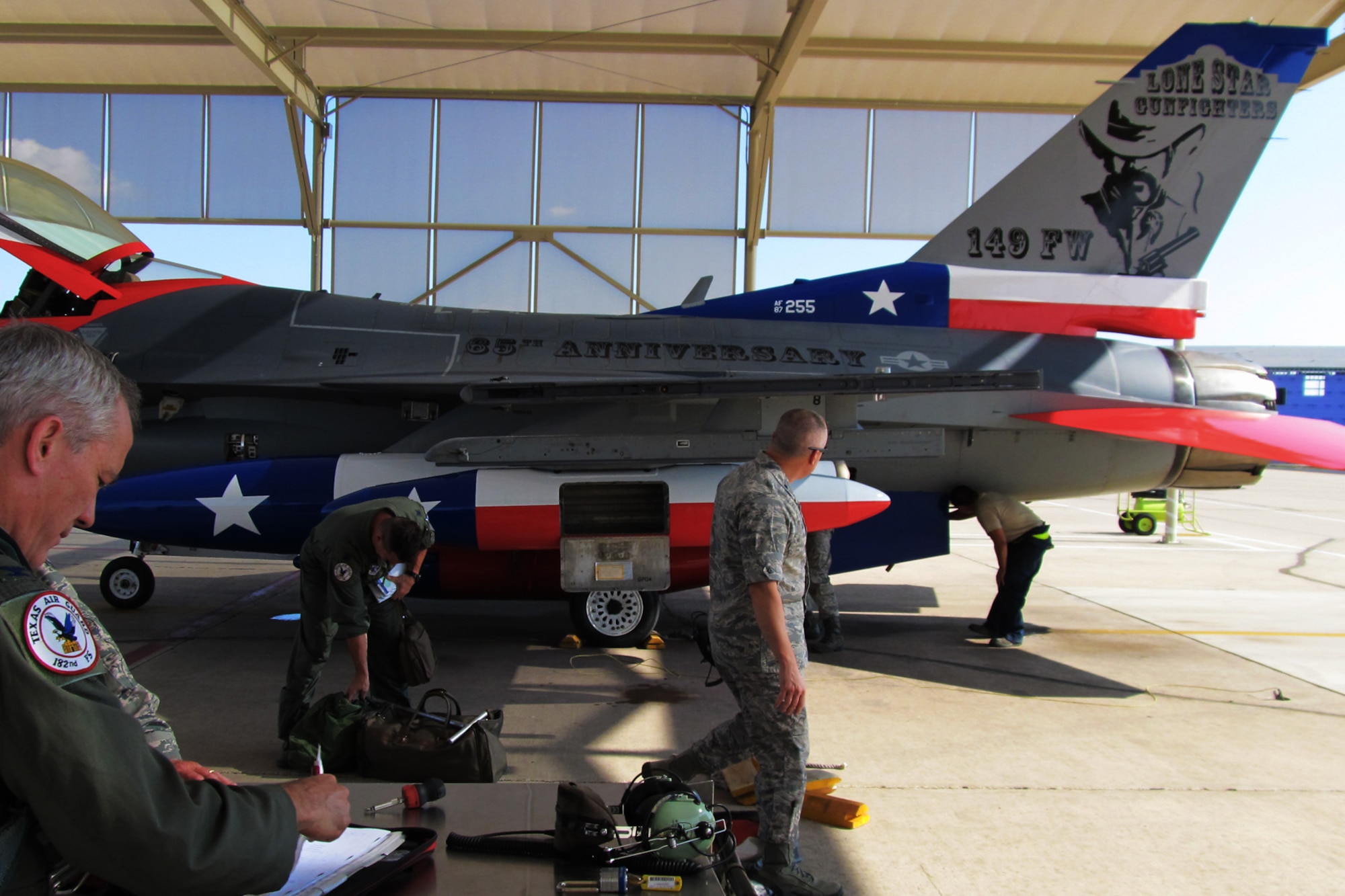 The Texas Air National Guard's 149th Fighter Wing's flagship F-16 returning to Lackland Air Force Base after being painted to honor the 65th anniversary of the unit's affiliation with the Air National Guard, Sept. 29, 2011.  Colonel (Col.) John Kane (left), wing commander, preparing the aircraft's forms for return to maintenance personnel.  (Air National Guard photo by Staff Sgt. Phil Fountain/Released)