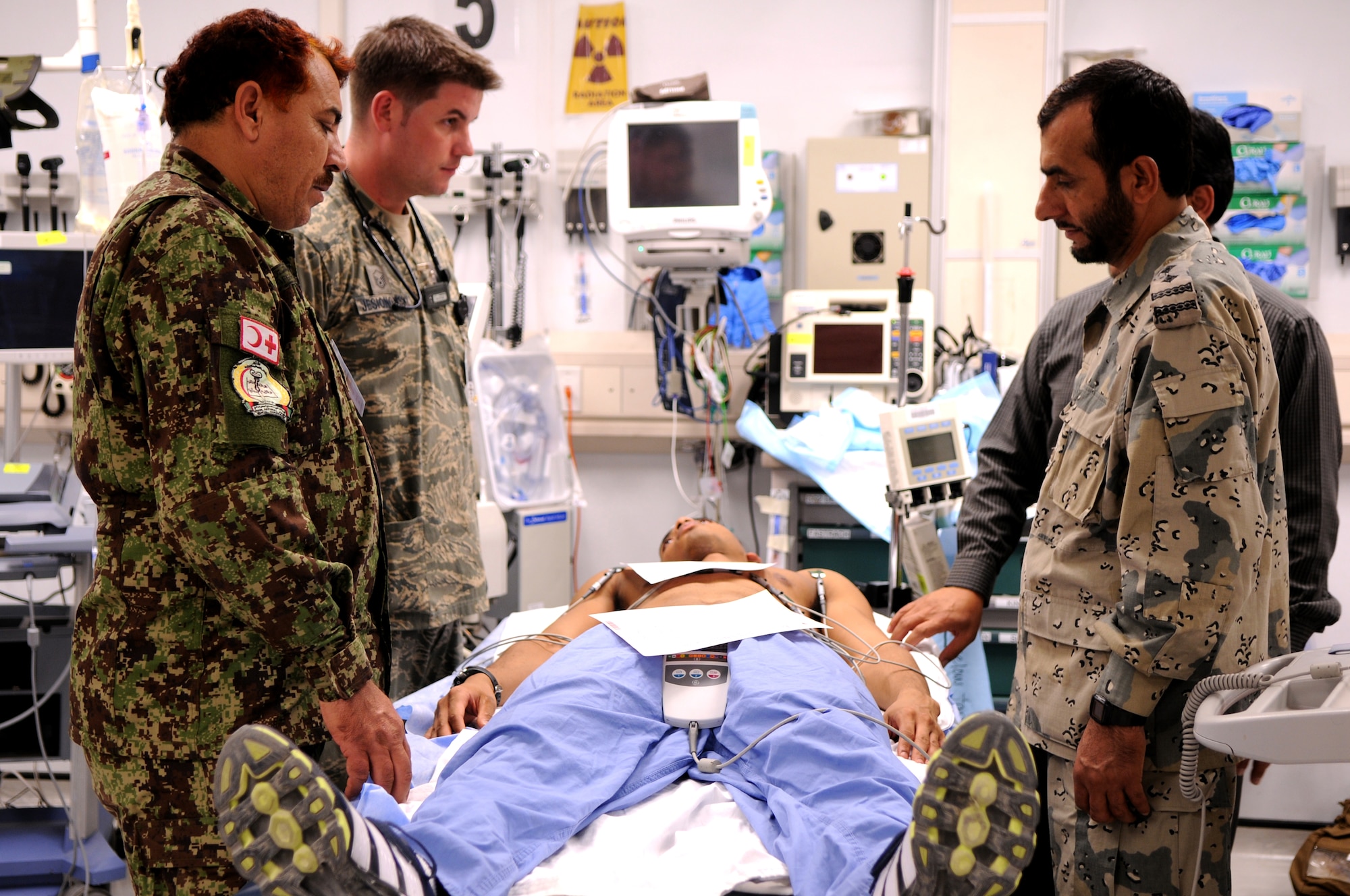 BAGRAM AIRFIELD, Afghanistan -- Master Sgt. James Jesionowski, 455th Expeditionary Medical Group emergency department flight chief, explains how to use an electrocardiogram machine to Capt. Nematullah, Physician Assistant, 2nd Brigade, 203rd Afghan National Army Corps. and Senior Capt. Abdul Hadi, Dentist, Afghan Border Police, 1st Zone Headquarters, as part of the Afghan Trauma Mentorship Program at Craig Joint Theatre Hospital here, Sept. 22, 2011. The ATMP is a joint effort between coalition partners and Airmen from the 455 EMDG designed to familiarize Afghan medical professionals with modern medical procedures and equipment. (U.S. Air Force photo/Senior Airman Krista Rose)  