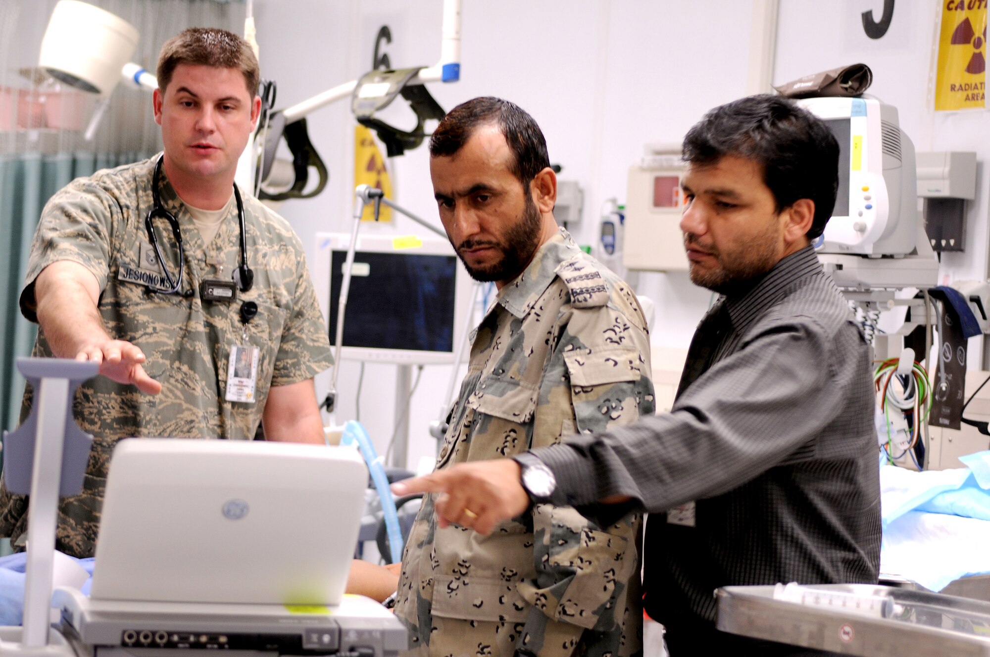 BAGRAM AIRFIELD, Afghanistan -- Master Sgt. James Jesionowski, 455th Expeditionary Medical Group emergency department flight chief, explains how to use an electrocardiogram machine to Senior Capt. Abdul Hadi, Dentist, Afghan Border Police, 1st Zone Headquarters, as part of the Afghan Trauma Mentorship Program at Craig Joint Theatre Hospital here, Sept. 22, 2011. The ATMP is a joint effort between coalition partners and Airmen from the 455 EMDG designed to familiarize Afghan medical professionals with modern medical procedures and equipment. (U.S. Air Force photo/Senior Airman Krista Rose)  
