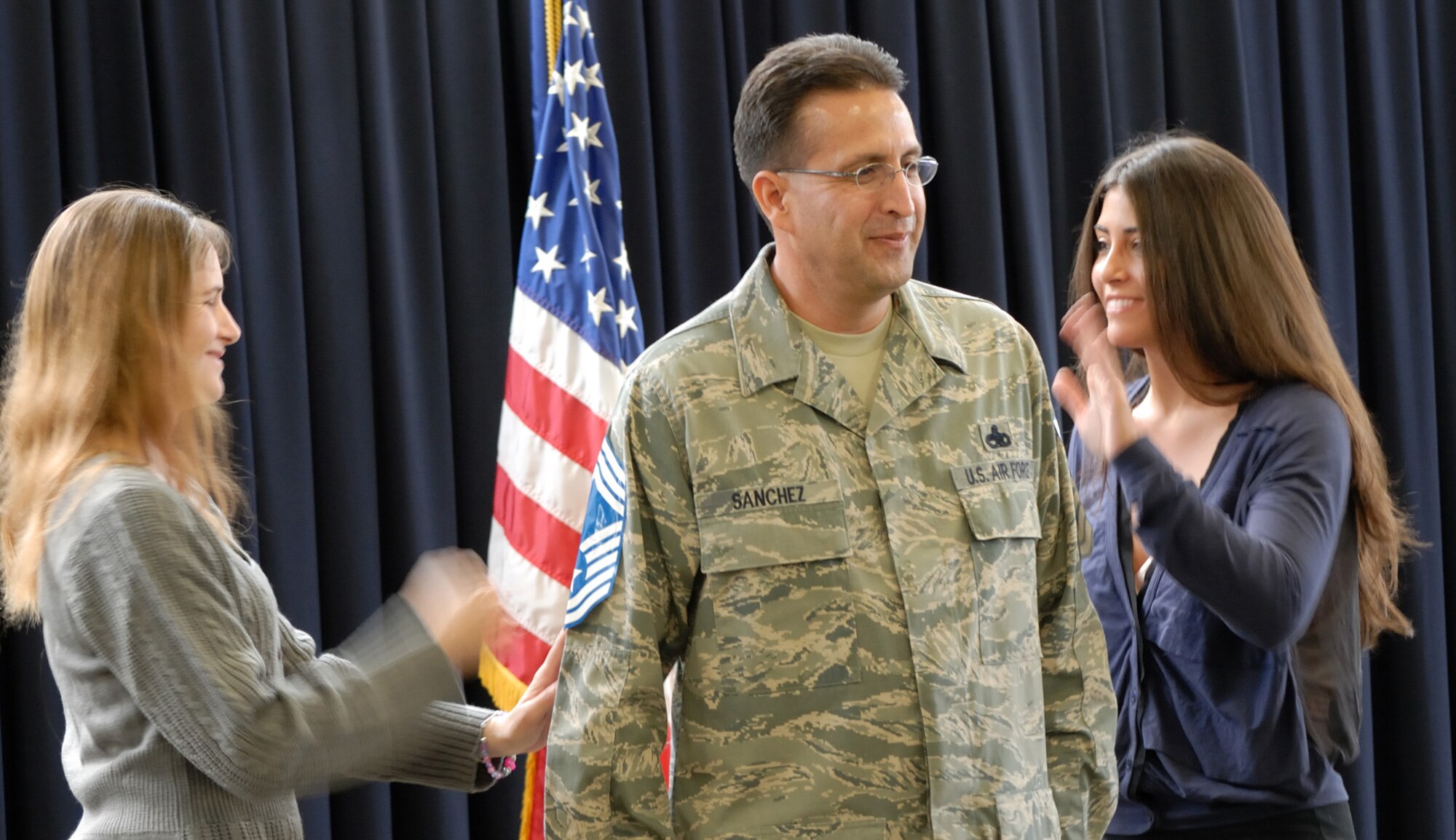 Chief Master Sgt. David Sanchez, 446th Maintenance Squadron fabrication shop flight chief, has his newly aquired rank "secured" to him by his girlfriend Jennifer Delucia (left), who is also a technical sergeant and historian for the 446th Airlift Wing, and his daughter Samantha, at his promotion ceremony, Oct. 1, 2011 at McChord Field, Wash. (U.S. Air Force photo by Chief Master Sgt. David Marston)