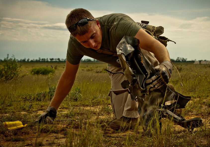 Staff Sgt. Aaron Carroll, an explosive ordnance disposal technician with the 325th Civil Engineer Squadron, searches for a vehicle identification number among the wreckage of a pick-up truck Sept. 28 on the Eglin Air Force Base range.  The investigation was part of the FBI's large vehicle post blast school attended by state and local law enforcement agencies as well as Navy and Air Force explosive ordnance disposal technicians. Three vehicles were blown up to create the crime scenes that students would investigate. The week-long course was the second held on Eglin with 67 students representing 18 different U.S. agencies. (U.S. Air Force photo/ Samuel King Jr.)