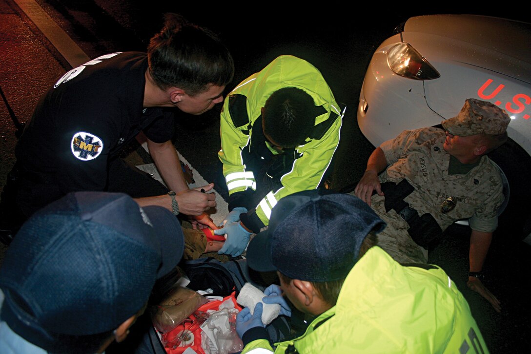 Emergency responders rush to assist Staff Sgt. Jarod E. Vedsted, with Military Police District North, who was role playing as an officer wounded by terrorists during the scenario-based exercise Constant Vigilance on Camp Courtney Oct. 4.