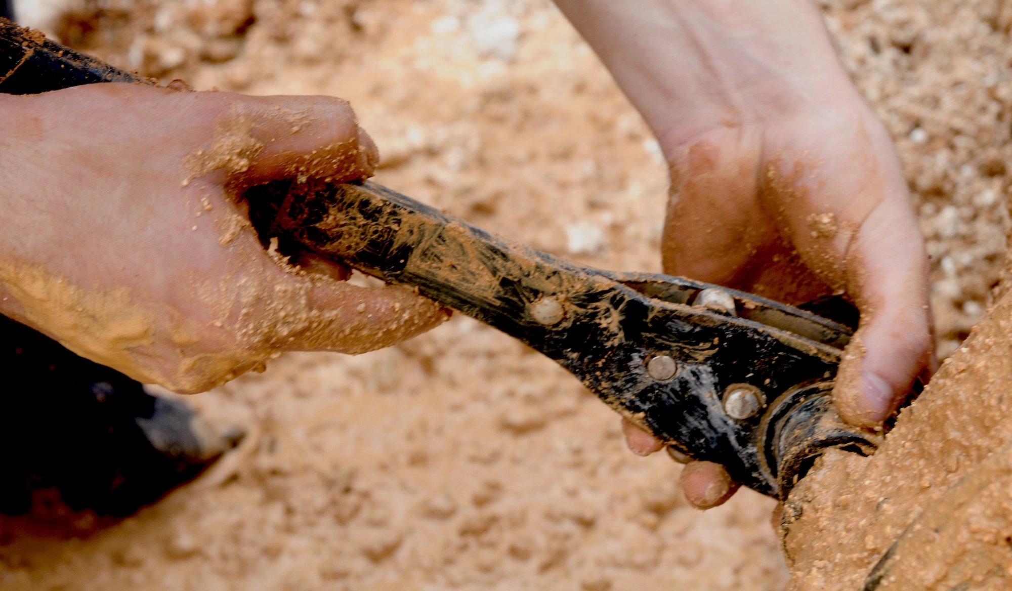 YIGO, Guam—A member of the 36th Civil Engineer Squadron removes a coupling during a water pipe repair here, Oct. 1. It took members from the 36 CES six hours after responding to replace the broken pipeline and begin to fill the hole made from the repair. (U.S. Air Force photo by Senior Airman Benjamin Wiseman/Released)