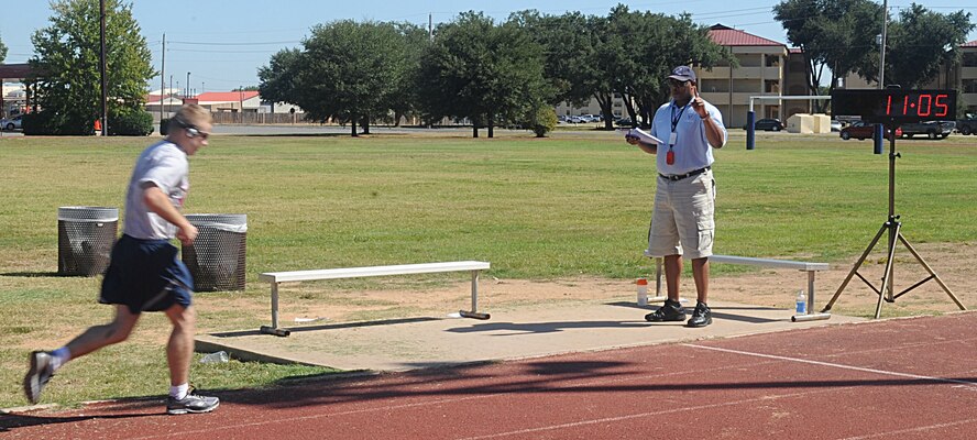 Robert Sedberry, 2nd Force Support Squadron, counts the laps that remain for Airmen during their physical fitness test run. The PT test, now administered twice a year for those passing below 90, requires Airmen to complete a certain amount of push-ups and sit-ups in one minute, a 1.5 mile run and have their abdominal circumference measured. (U.S. Air Force photo/Senior Airman Kristin High)(RELEASED)