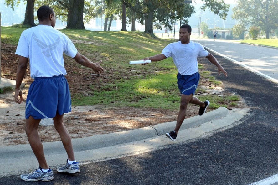 Airman 1st Class Michael Johnson passes a baton to Senior Airman Demetrius Taylor during Wing Sports Day at Seymour Johnson Air Force Base, N.C., Sept. 30, 2011. Johnson ran two miles during a 10 mile team relay. Johnson is a 4th Component Maintenance Squadron precision measurement equipment laboratory technician and hails from New Orleans. Taylor is a 4 CMS test measurement diagnostic equipment technician and hails from Melbourne, Fla. (U.S. Air Force photo by Senior Airman Whitney Stanfield)