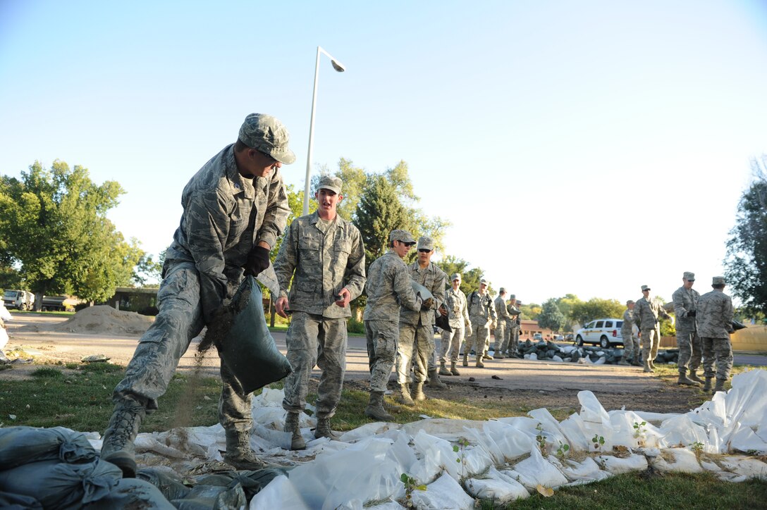 Cadet 2nd Class Zach Mattee hands a leaking sandbag to Cadet 3rd Class Steve Kearney, as the cadets removed sandbags from levees as part of flood relief and cleanup efforts Sept. 30 in Pierre, S.D.  Each sandbag weighed between 30 and 80 pounds, depending on how full the sandbag was, and if it was waterlogged. 
(U.S. Air Force Photo/John Van Winkle)
