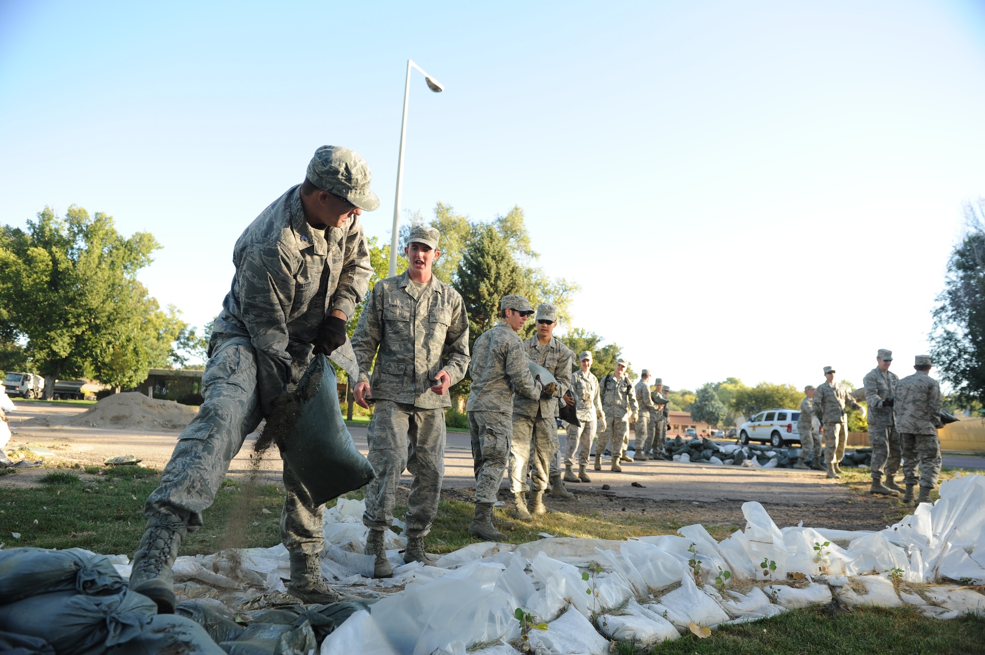 Cadet 2nd Class Zach Mattee hands a leaking sandbag to Cadet 3rd Class Steve Kearney, as the cadets removed sandbags from levees as part of flood relief and cleanup efforts Sept. 30 in Pierre, S.D.  Each sandbag weighed between 30 and 80 pounds, depending on how full the sandbag was, and if it was waterlogged. 
(U.S. Air Force Photo/John Van Winkle)
