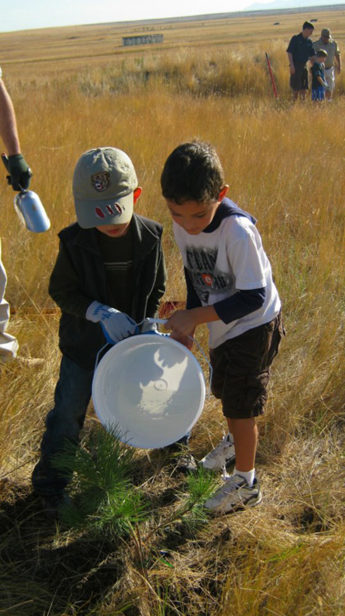 Jaxx Zimmerli-Mann (left) and Izak Peak, both 6, from Cub Scout Pack 43 water a ponderosa pine tree they planted near Pow Wow Park Sept. 24. (Courtesy photo)