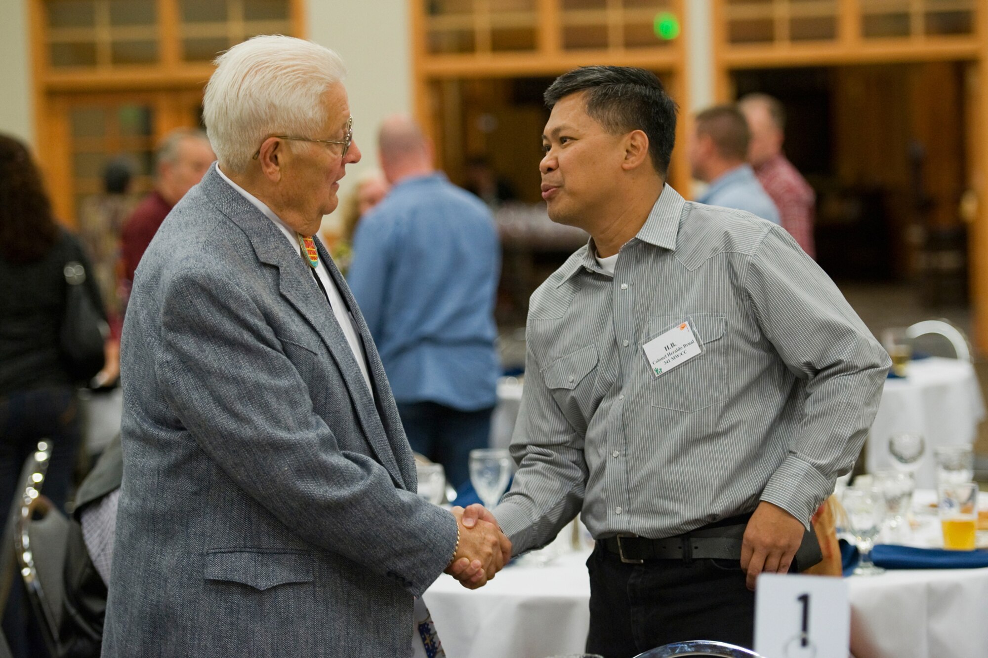 Col. Heraldo Brual, 341st Missile Wing commander, introduces himself to retired Air Force Maj.Steve Kubick, who also founded Operation Happy Holidays when he was employed at 1st Liberty Federal Credit Union.  He continues to be heavily involved with the program today. He was one of many who were thanked for their ongoing support that evening. (U.S. Air Force photo/Beau Wade)