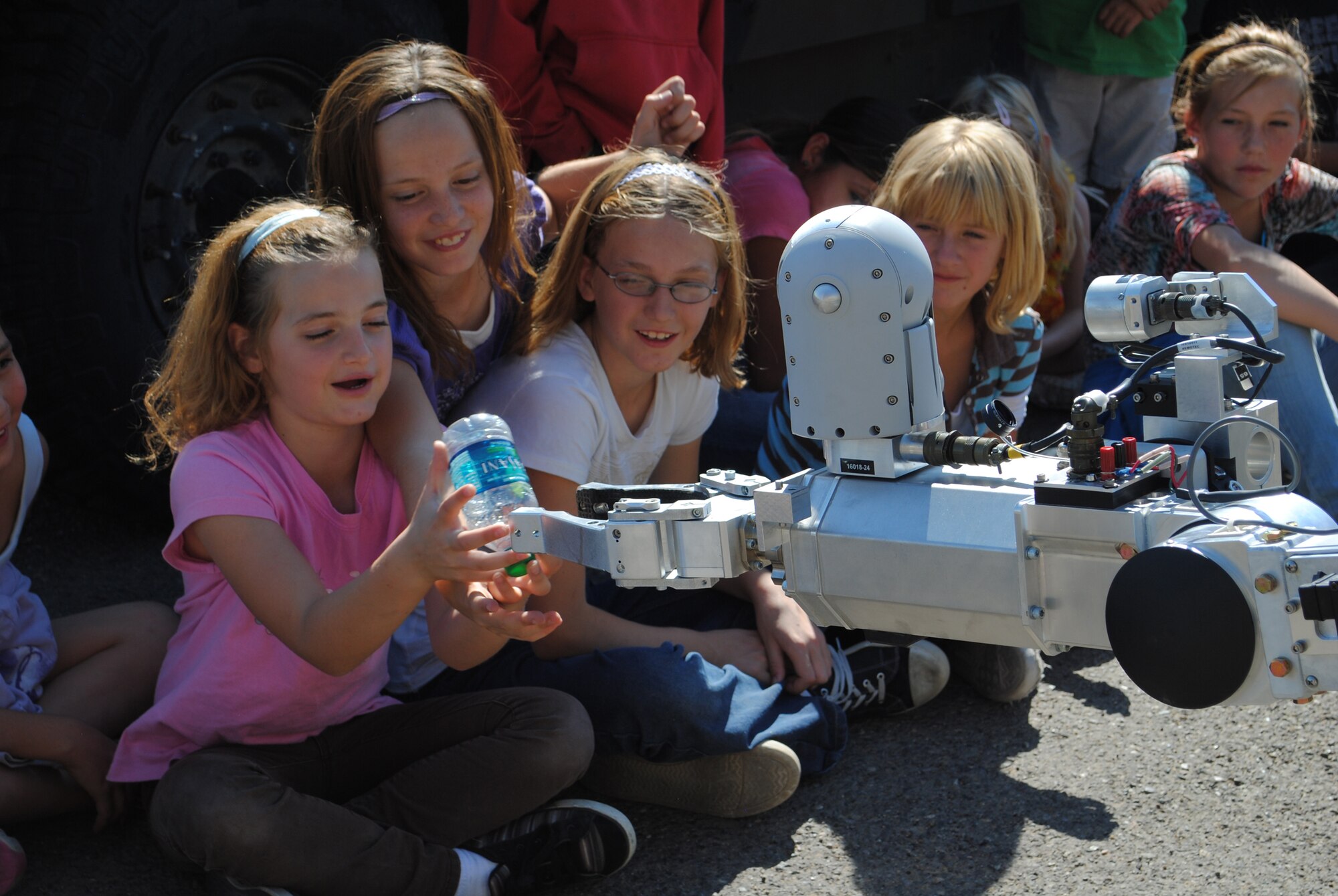 From left, Annie, 8; Tory, 9; and Savannah, 10, take an empty water bottle from the arm of one of Malmstrom's Explosive Ordnance Disposal robots.  The EOD team also showed members of the Big Brothers, Big Sisters program an example of an Improvised Explosive Device and the protective gear they wear.  (U.S. Air Force photo/Airman Cortney Paxton)
