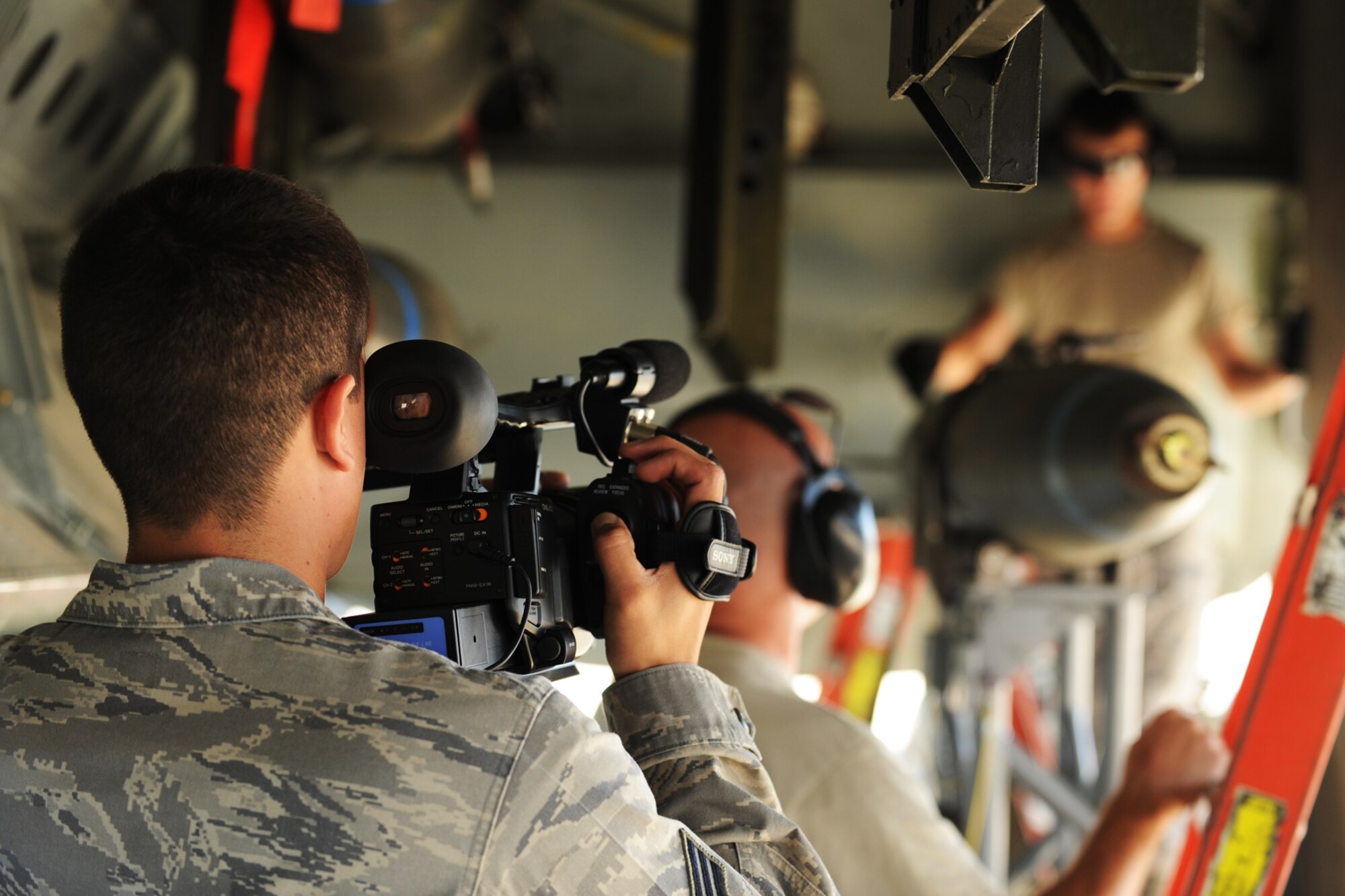 U.S. Air Force Senior Airman Anthony Gamez, 3rd Combat Camera Squadron videographer, records video of U.S. Air Force Master Sgt. Thomas Beckman and Staff Sgt. Kyle Bailey, 307th Aircraft Maintenance Squadron weapons loaders, as they practice loading a simulated MK-82, 500 pound general purpose bomb, into the bomb bay of a 307th Bomb Wing B-52 Stratofortress, Barksdale Air Force Base, La., Sept. 30, 2011. Beckman and Bailey are practicing for the upcoming Global Strike Challenge, which is an Air Force bomber competition, and members of the 3rd CCS are tasked with creating videos of each competing team, which will be shown during the competition's awards ceremony. (U.S. Air Force photo by Master Sgt. Greg Steele/Released)