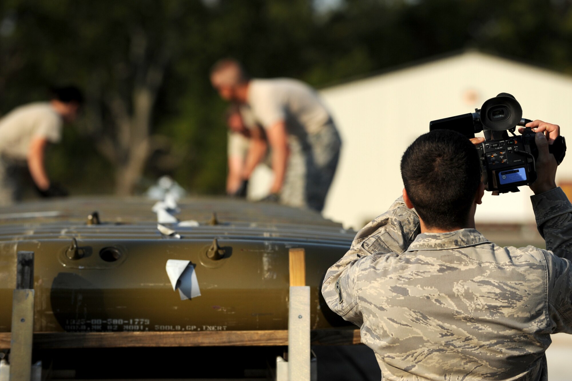 U.S. Air Force Senior Airman Anthony Gamez, 3rd Combat Camera Squadron (CCS) videographer, records video of 307th Maintenance Squadron munitions technicians as they assemble simulated MK-82, 500 pound general purpose bombs, during a practice bomb-build in preparation for the 2nd annual Global Strike Challenge competition, Barksdale Air Force Base, La., Sept. 30, 2011. The 3rd CCS is tasked with creating video representations of each competition team, which will be shown during the Global Strike Challenge awards ceremony. (U.S. Air Force photo by Master Sgt. Greg Steele/Released)