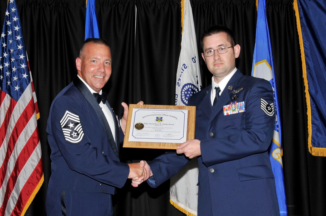 McGHEE TYSON AIR NATIONAL GUARD BASE, Tenn. - Tech. Sgt. Jonathan Sutherland, right, receives the distinguished graduate award for NCO Academy Class 11-7 at The I.G. Brown Air National Guard Training and Education Center here from Command Chief Master Sgt. Kevin Candler, Sept. 21, 2011.  The distinguished graduate award is presented to students in the top ten percent of the class.  It is based on objective and performance evaluations, demonstrated leadership, and performance as a team player. (U.S. Air Force photo by Master Sgt. Kurt Skoglund/Released)