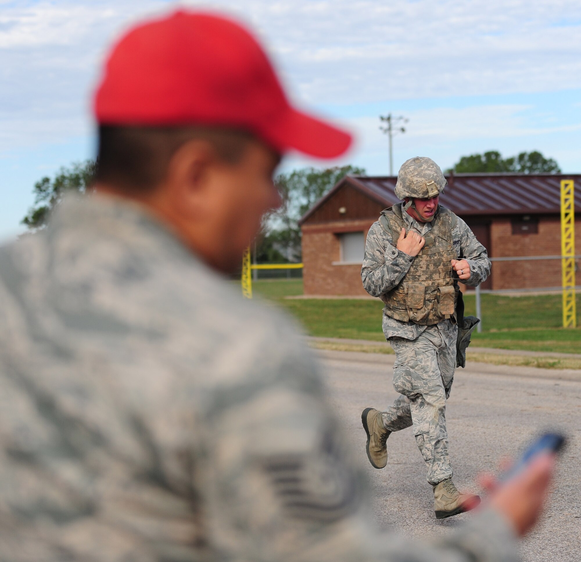 Tech. Sgt. Roy Chavez, 509th Security Forces Squadron, keeps time as Senior Airman Joseph Robin, 509th SFS, finishes the running portion of the Air Force Global Strike Command Challenge try-outs here Sept. 21. Participants ran almost two miles with and without gas masks while wearing Kevlar helmets and vests. (U.S. Air Force photo/Senior Airman Nick Wilson) (RELEASED)