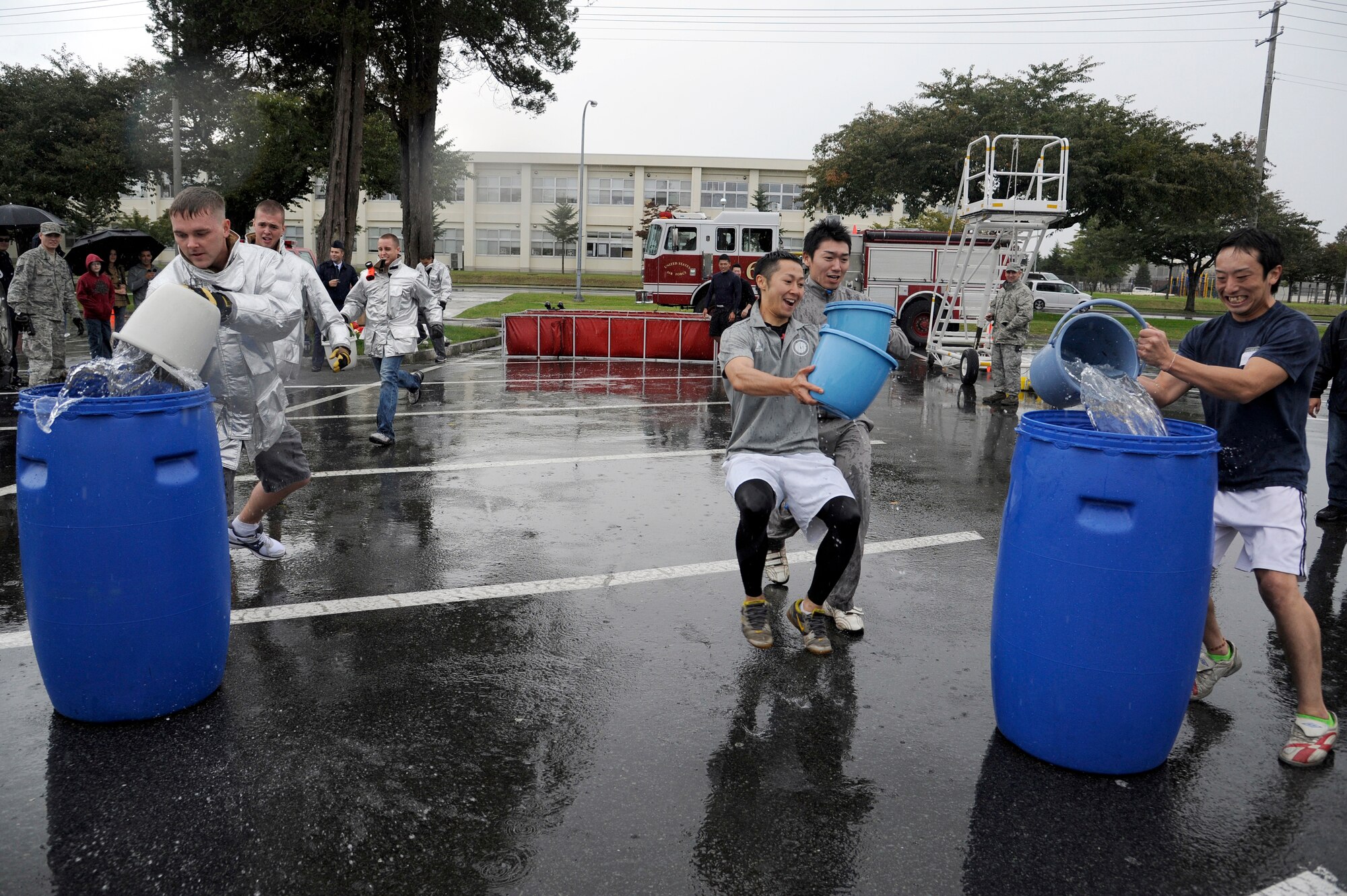 MISAWA AIR BASE, Japan -  Firefighters from the 35th Civil Engineer Squadron race against firefighters from Towada City during the bucket brigade event part of the fire muster competition held at the base exchange parking lot here Oct. 2. Firefighters from the 35 CES along with firefighters from Misawa City and Towada City participated in a fire muster to kick off Fire Prevention Week. Fire Prevention Week was established to commemorate the Great Chicago Fire, the tragic 1871 blaze that killed more than 250 people, left 100,000 homeless, destroyed more than 17,400 structures and burned more than 2,000 acres. In 1920, President Woodrow Wilson issued the first National Fire Prevention Day proclamation, and since 1922, Fire Prevention Week has been observed on the Sunday through Saturday period in which October 9 falls. (U.S. Air Force photo/Tech. Sgt. Marie Brown)
