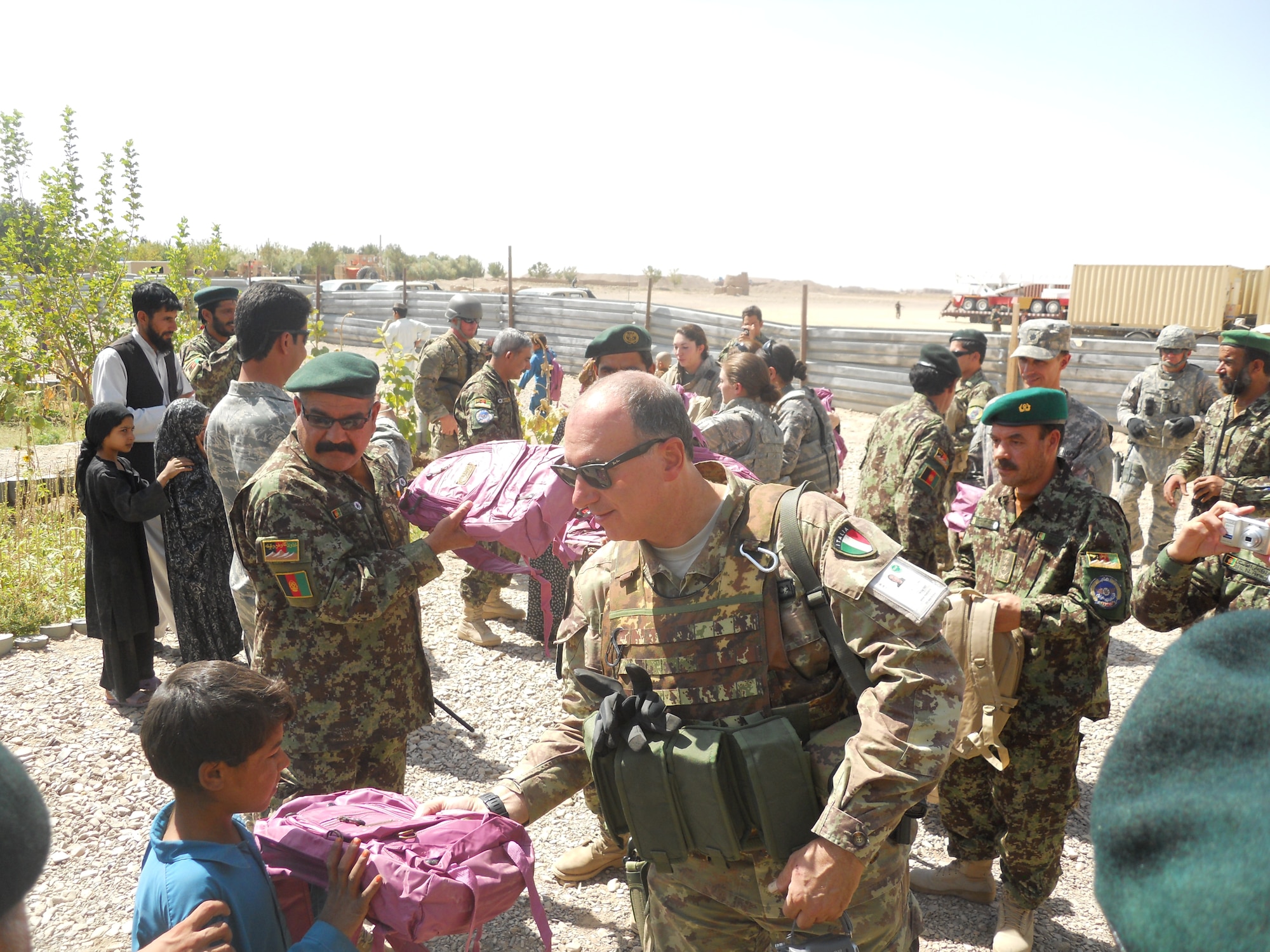Coalition members from the 838th Air Expeditionary Advisory Group, hand out backpacks in a local village near the base. Members participate in the humanitarian missions with hopes of building relationships with locals. (U.S. Air Force courtesy photo)