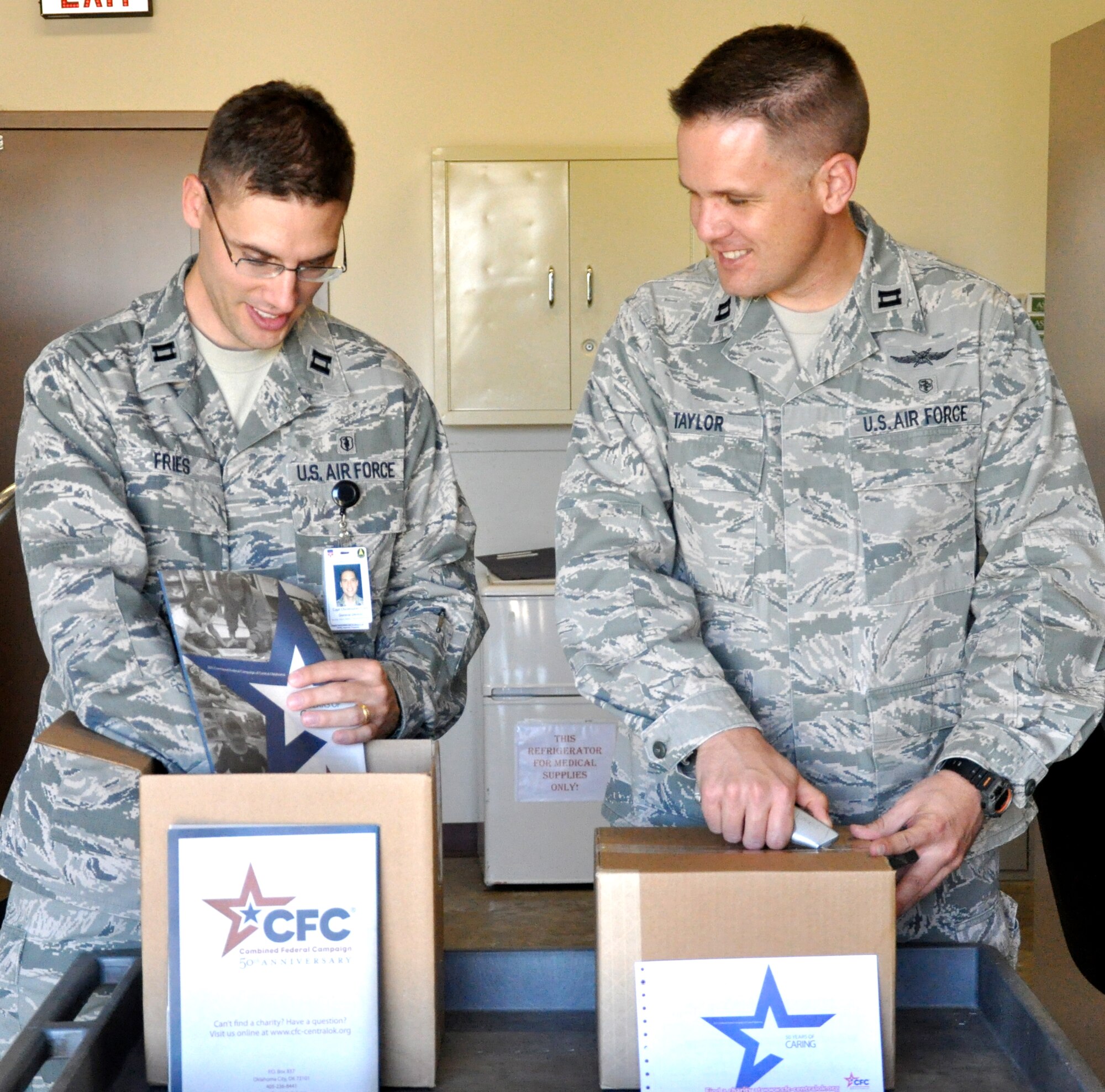 Capt. Lewis Taylor, right, the 71st Flying Training Wing Combined Federal Campaign coordinator this year, and Capt. Christopher Fries, the 71st Medical Group CFC coordinator, open boxes of CFC donation ships and charities booklets in preparation for the campaign kickoff Oct. 3. (U.S. Air Force photo/ Airman 1st Class Frank John Casciotta)