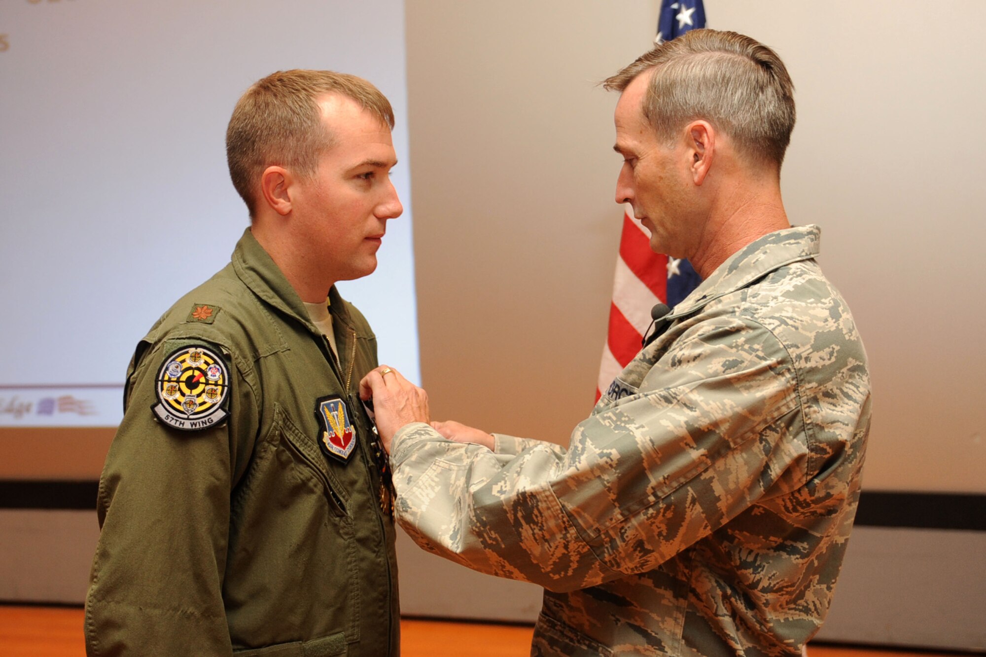 Maj. Ryan T. Hayde, an A-10 Thunderbolt II pilot with the 57th Wing, is awarded the Distinguished Flying Cross from Brig. Gen. Terrence O'Shaunessy during a commander's call Sept. 30, 2011, in the base theater at Nellis Air Force Base, Nev. Hayde received the Distinguished Flying Cross for extraordinary achievement during an aerial flight while deployed to Kandahar Air Base, Afghanistan. He was also awarded the Single Mission Air Medal and the Air Medal. (U.S. Air Force photo by Staff Sgt. Taylor Worley/Released)
