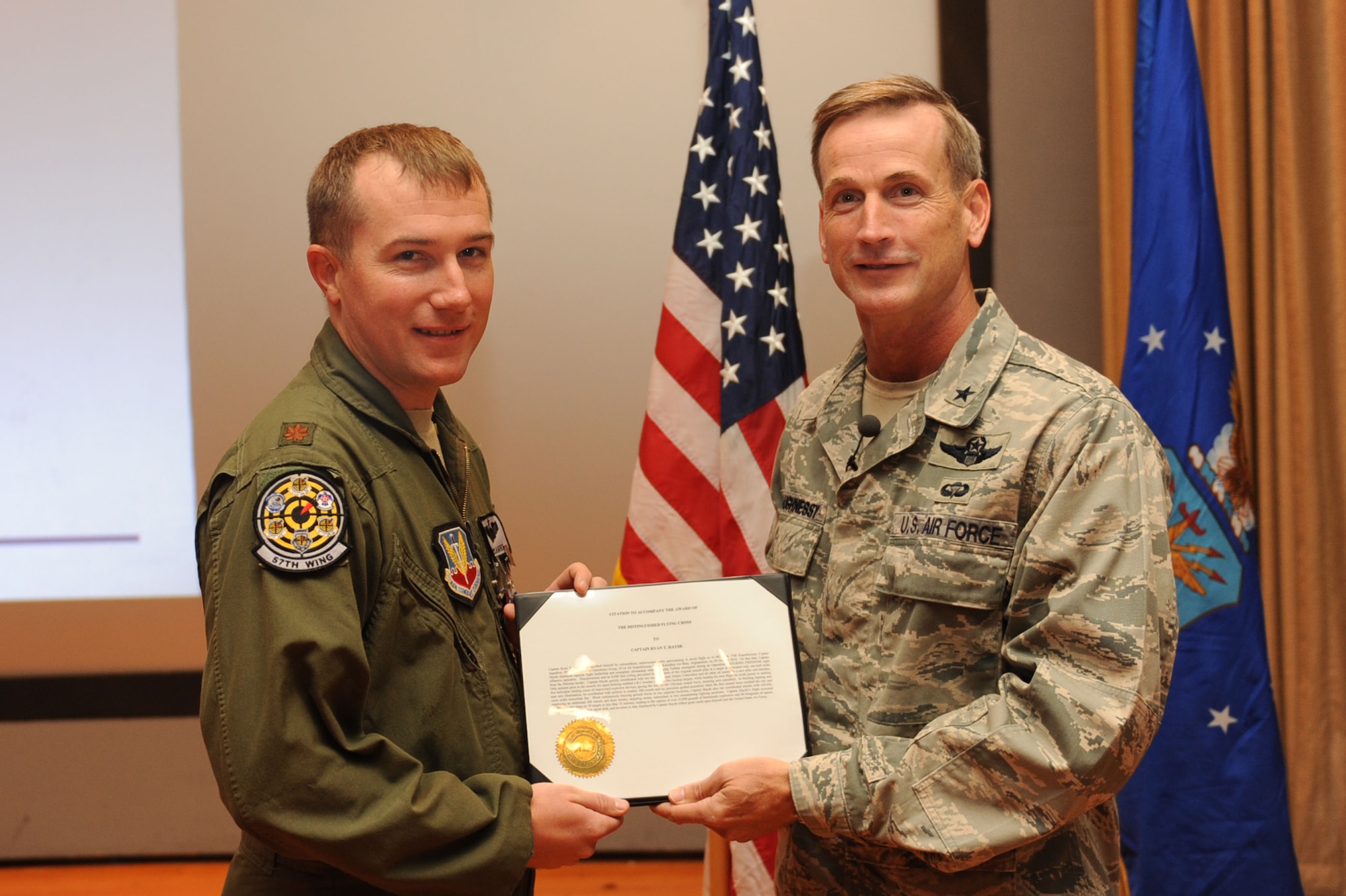 Maj. Ryan T. Hayde, an A-10 Thunderbolt II pilot with the 57th Wing, is awarded the Distinguished Flying Cross from Brig. Gen. Terrence O'Shaunessy during a commander's call Sept. 30, 2011, in the base theater at Nellis Air Force Base, Nev. Hayde received the Distinguished Flying Cross for extraordinary achievement during an aerial flight while deployed to Kandahar Air Base, Afghanistan. He was also awarded the Single Mission Air Medal and the Air Medal. (U.S. Air Force photo by Staff Sgt. Taylor Worley/Released)
