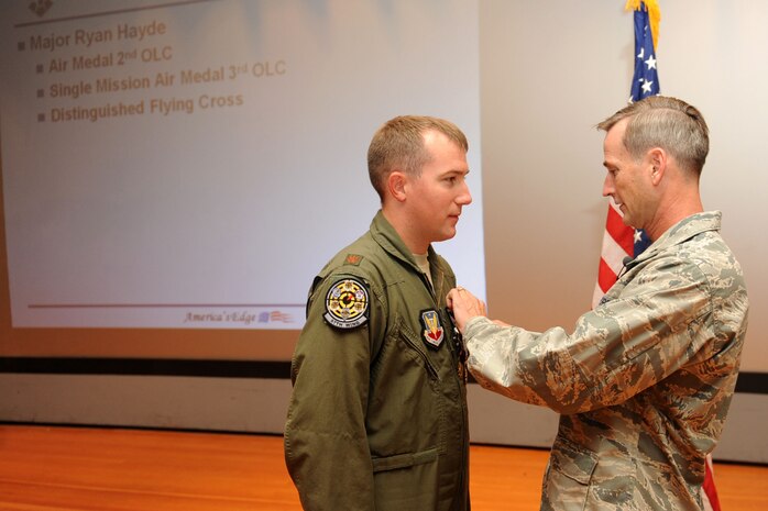 Maj. Ryan T. Hayde, an A-10 Thunderbolt II pilot with the 57th Wing, receives the Distinguished Flying Cross from Brig. Gen. Terrence O'Shanughnessy during a commander's call Sept. 30, 2011, in the base theater at Nellis Air Force Base, Nev. Hayde received the Distinguished Flying Cross for extraordinary achievement during an aerial flight while deployed to Kandahar Air Base, Afghanistan. He was also awarded the Single Mission Air Medal and the Air Medal. (U.S. Air Force photo by Staff Sgt. Taylor Worley/Released)