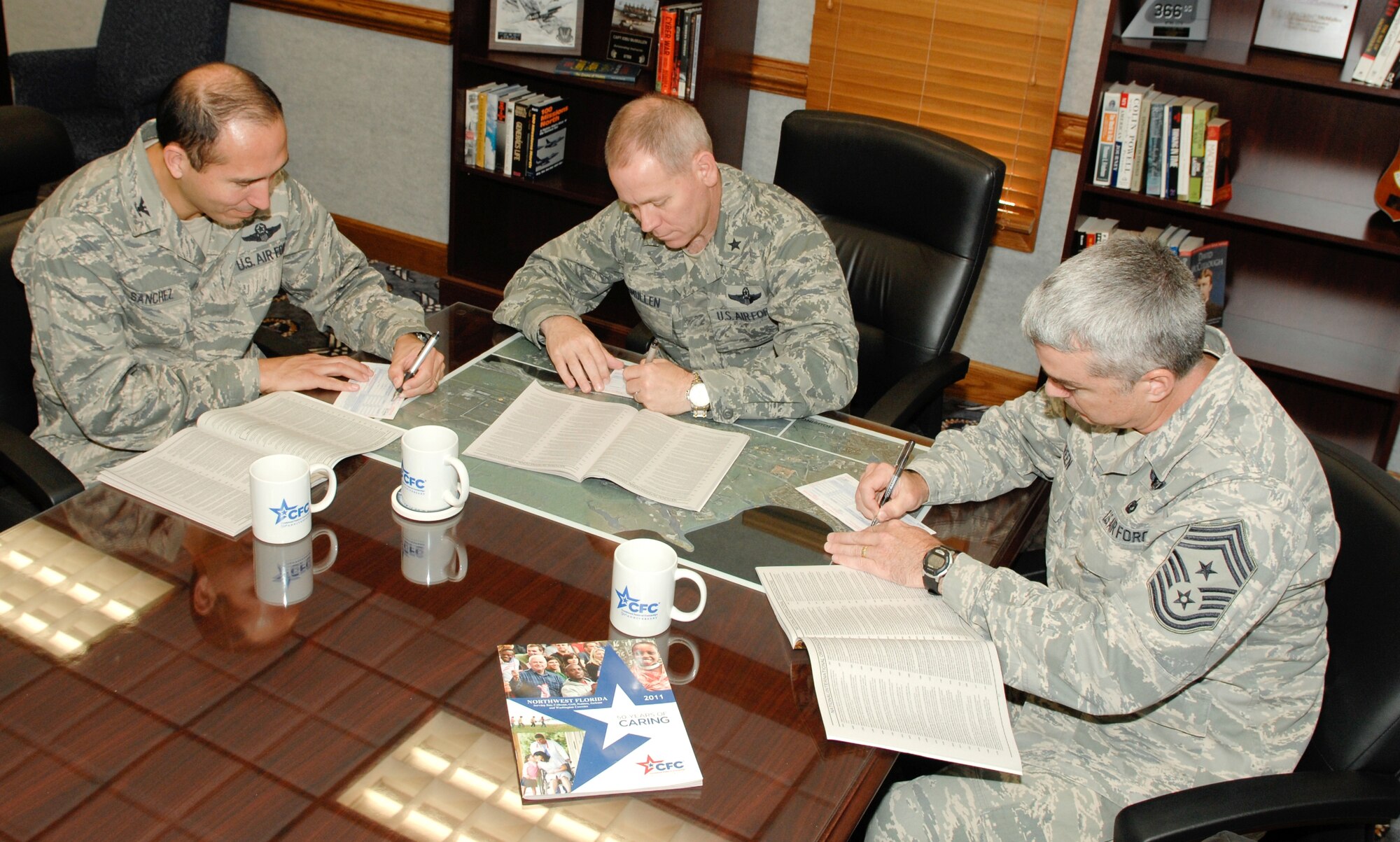 Brigadier Gen. John McMullen, 325th Fighter Wing commander, Colonel Orlando Sanchez, 325th FW vice commander, and Command Chief Master Sgt. Jackie Green, 325th FW command chief, begin to fill out their Combined Federal Campaign forms for Tyndall’s 2011 season, beginning Oct. 11. (US Air Force photo by Chris Cokeing)