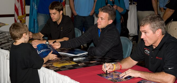 A fan receives an autograph from A.J. Allmendinger (middle), the No. 43 car driver in the NASCAR Sprint Cup series, at the NASCAR Social Sept. 30, 2011, at Dover Air Force Base, Del. Bobby Labonte (right), the No. 47 car driver in the NASCAR Sprint Cup series, and David Ragan, the No. 6 car driver in the NASCAR Sprint Cup series, also signed autographs. The social featured a live band, food, a miniature racecar track, children’s entertainment and more. (U.S. Air Force photo by Airman 1st Class Samuel Taylor)  