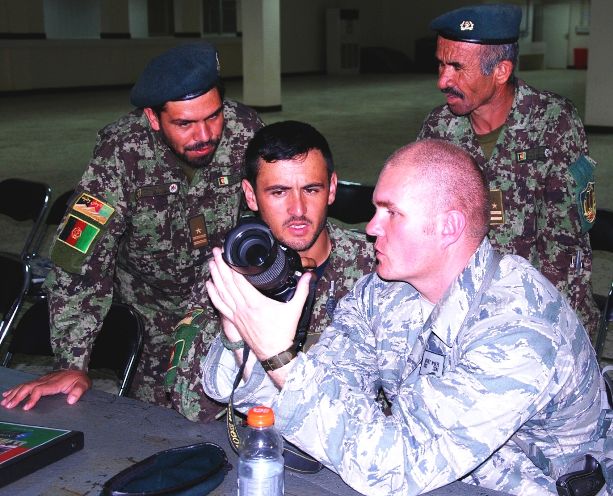 Air Force Tech. Sgt. Jeffrey Wolfe, Air Force Recruiting Service national advertising photographer, explains a camera's features to public affairs officers of the Afghan National Army's 205th Corps during a public affairs seminar at Camp Hero Sept. 17 in Kandahar.  The three-day public affairs seminar focused on information gathering and visual storytelling.  (Photo by ANA 205th Corps Public Affairs) 