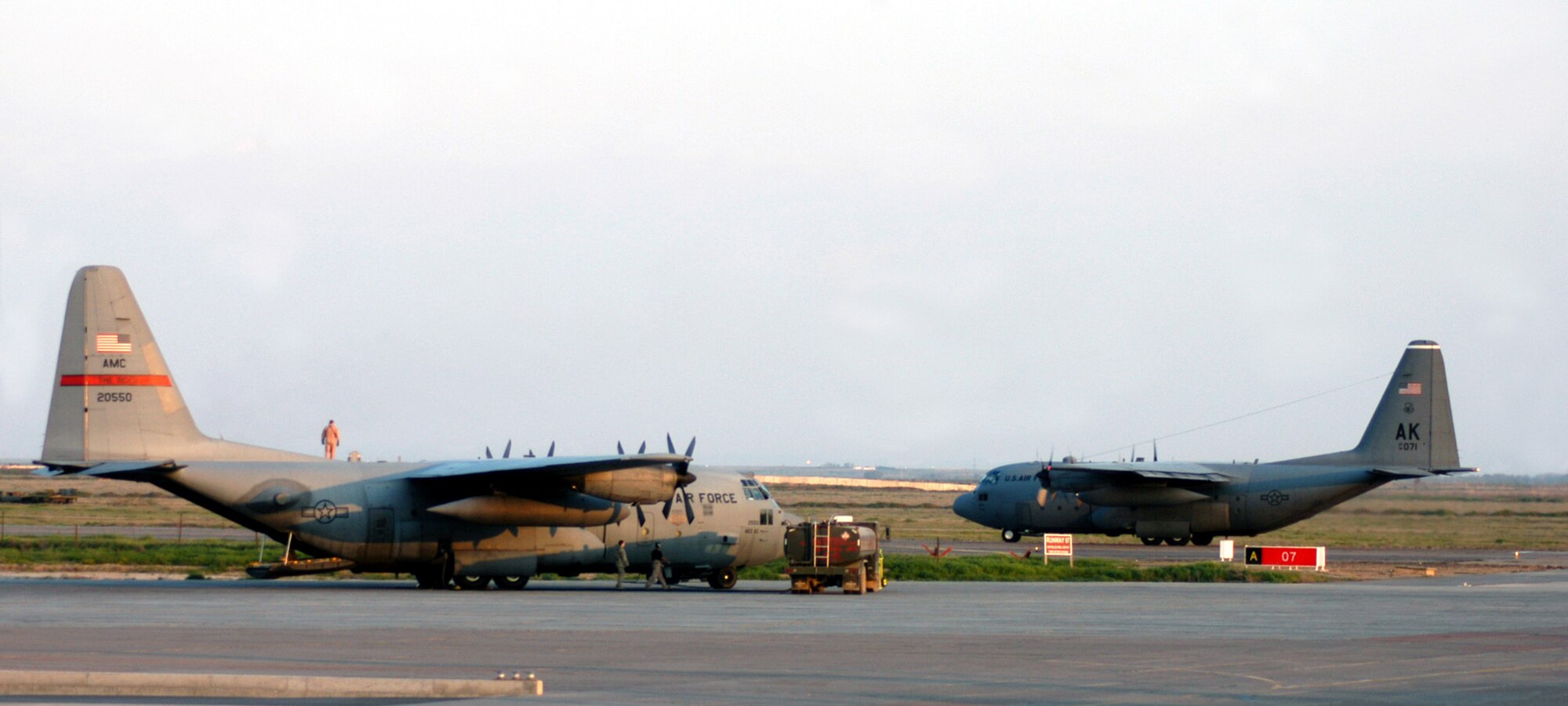 A C-130 Hercules (right), from the 3rd Wing, Joint Base Elmendorf-Richardson, Alaska, taxies out for an Operation Enduring Freedom mission while another C-130 aircraft from Air Mobility Command sits on the flight line at Karshi-Khanabad Air Base, Uzbekistan, on April 10, 2005.  (U.S. Air Force Photo/Master Sgt. Scott T. Sturkol)