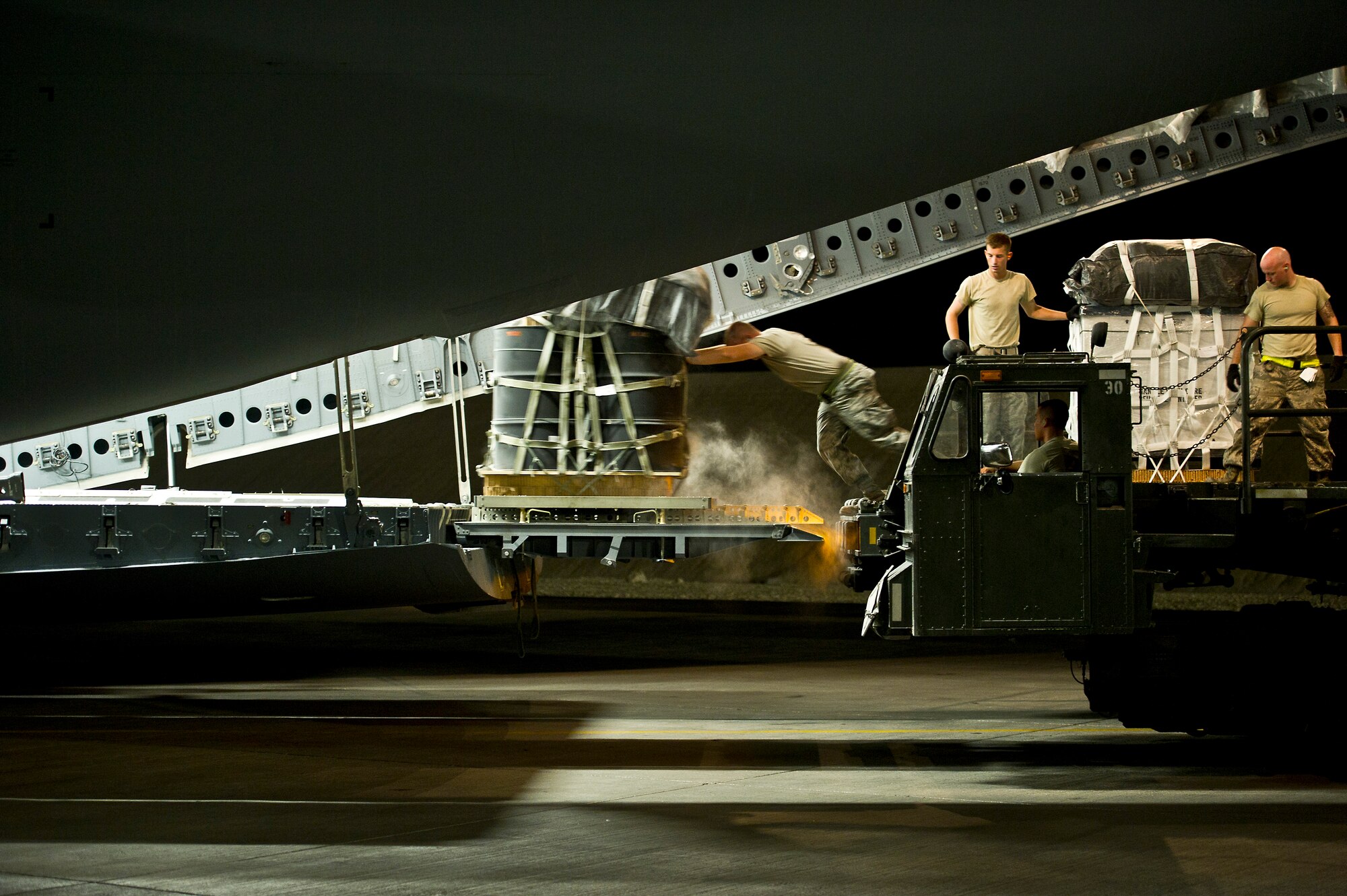 U.S. Air Force Airmen from the 379th Expeditionary Aircraft Maintenance Squadron push barrels of fuel aboard a C-17 Globemaster III on Sept 30, 2011. The crew of the C-17 will drop 40 bundles of supplies to a remote outpost in Afghanistan. Aerial delivery of critical supplies decreases the total number of resupply convoys conducted in high threat areas.  (U.S. Air Force Photo/Master Sgt. Jeffrey Allen)
