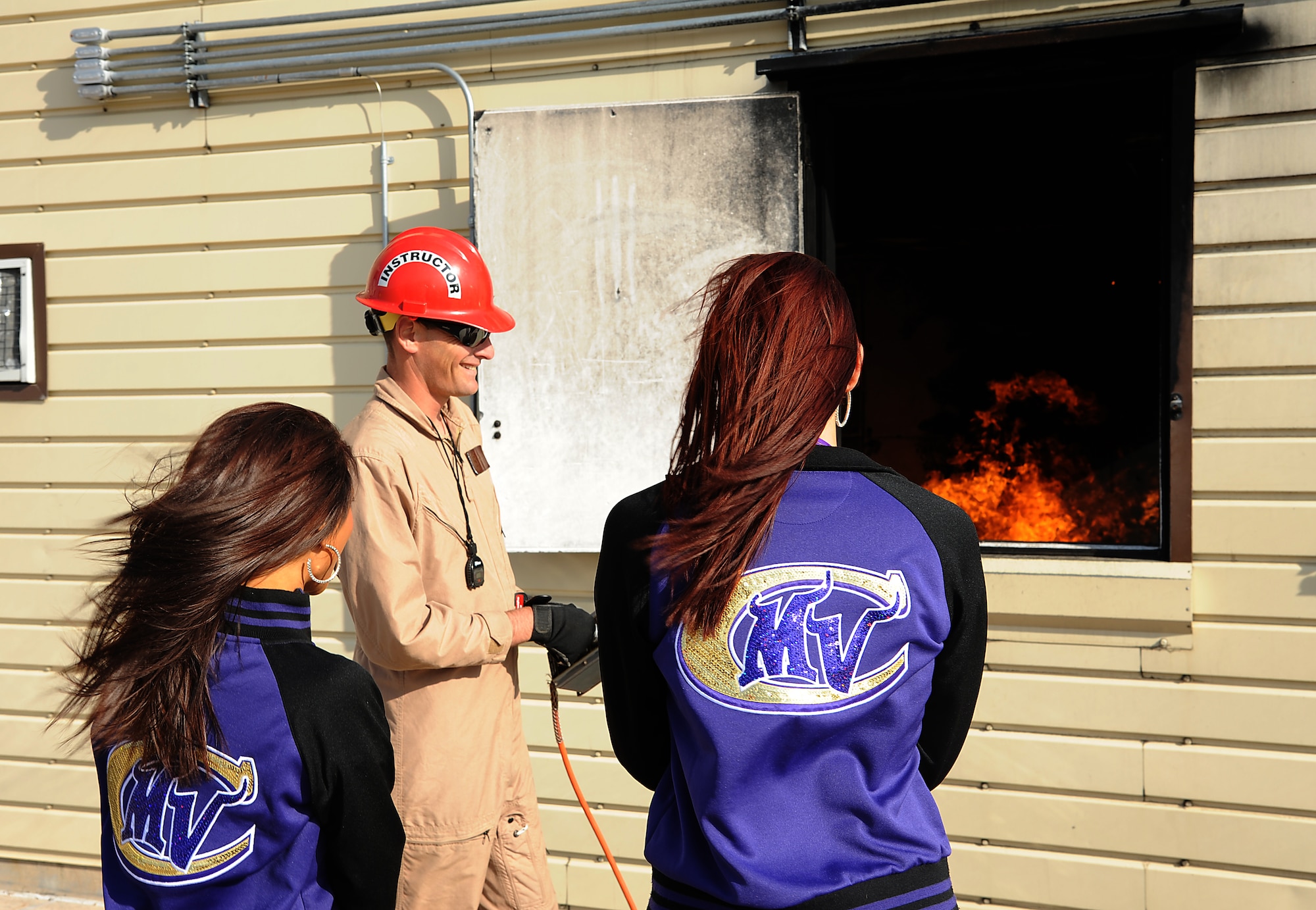 GOODFELLOW AIR FORCE BASE, Texas – A 312th Training Squadron Instructor shows two Minnesota Vikings cheerleaders how the interior fire trainer works during the cheerleaders’ tour of the Louis F. Garland Fire Academy here Sept 30. The cheerleaders visited Goodfellow to boost morale. (U.S. Air Force photo/Airman 1st Class Michael Smith)   