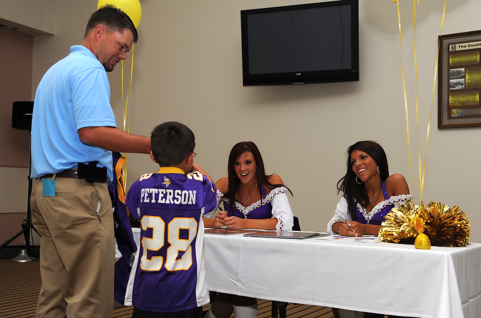 GOODFELLOW AIR FORCE BASE, Texas -- Two Minnesota Vikings cheerleaders greet a young fan during an autograph session at the Event Center here Sept. 30. The cheerleaders visited Goodfellow to boost morale. (U.S. Air Force photo/Airman 1st Class Michael Smith)   