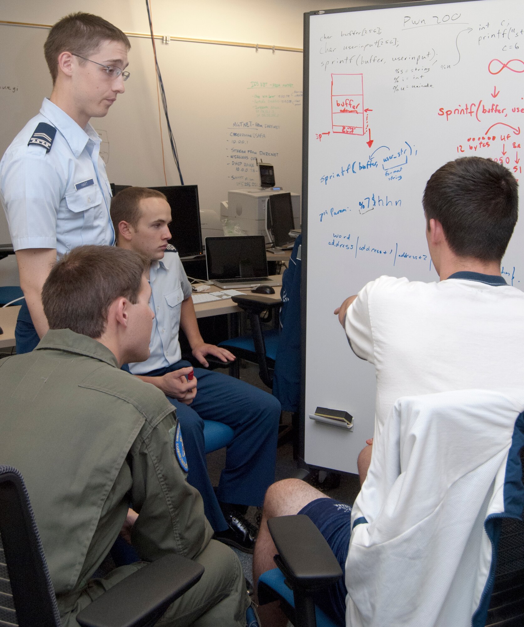 Clockwise from right: Cadet 2nd Class Josh Christman, Cadet 1st Class Chris Shields, Cadet 2nd Class Nathan Hart and Cadet 1st Class Jordan Keefer discuss how to conduct a string format attack during a cyber competition team meeting in the Air Force Academy's Cyberwarfare Lab Oct. 3, 2011. String format vulnerabilities exist in some software applications written using the C++ programming language and can allow attackers to gain administrative rights on remote systems. Keefer is the team's cadet in charge. (U.S. Air Force photo/Don Branum)