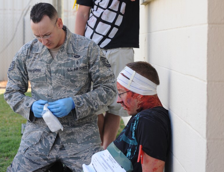 Tech. Sgt. Edward Staystork, 2nd Aerospace Medical Squadron, opens a bandage package while a volunteer with simulated wounds waits for treatment during a Major Accident Response Exercise on Barksdale Air Force Base, La., Oct. 5. The MARE was conducted to test the readiness of emergency response personnel after the base was hit by simulated severe storms and a tornado. (U.S. Air Force photo/Airman 1st Class Micaiah Anthony)(RELEASED)