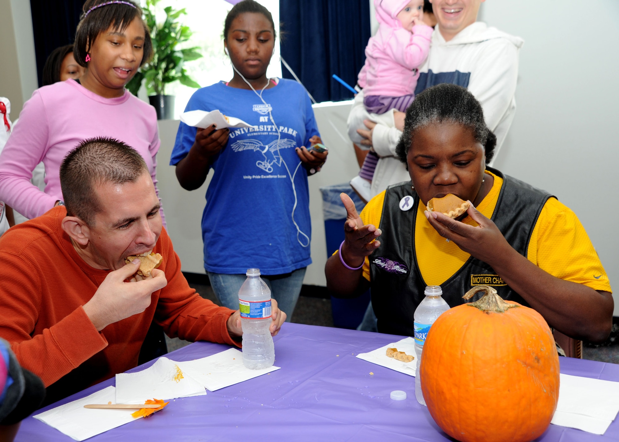 Staff Sgt. Brad Smith, 779th Medical Operations Squadron Behavior Medicine service NCO in charge, and Anna “Onyx” David, Queens of Sheba Motorcycle Club Washington D.C., devour 2 slices of pumpkin pie during the adult eating contest at the Pumpkin Bash in the Community Activity Center on Oct. 1. Smith won the contest using a stacking technique to eat both slices at the same time. The Pumpkin Bash was a Family Advocacy hosted event which kicked off domestic violence awareness month. (U.S. Air Force photo/Airman 1st Class Bahja J. Jones)