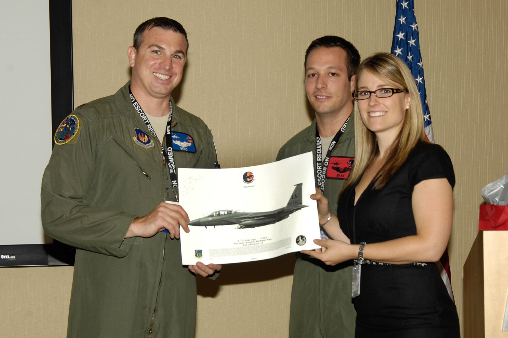 Maj. Ken Harney (left) and Capt. Tyler Stark, the crew from the F-15 Strike Eagle that crashed during Libyan operations in March, present a photo to Kate Stowe, Combat Survivor Evader Locator program manager on Sept. 30. The crew took part in a special event marking delivery of the 50,000th CSEL radio system. (U.S. Air Forcephoto by Linda LaBonte Britt)
