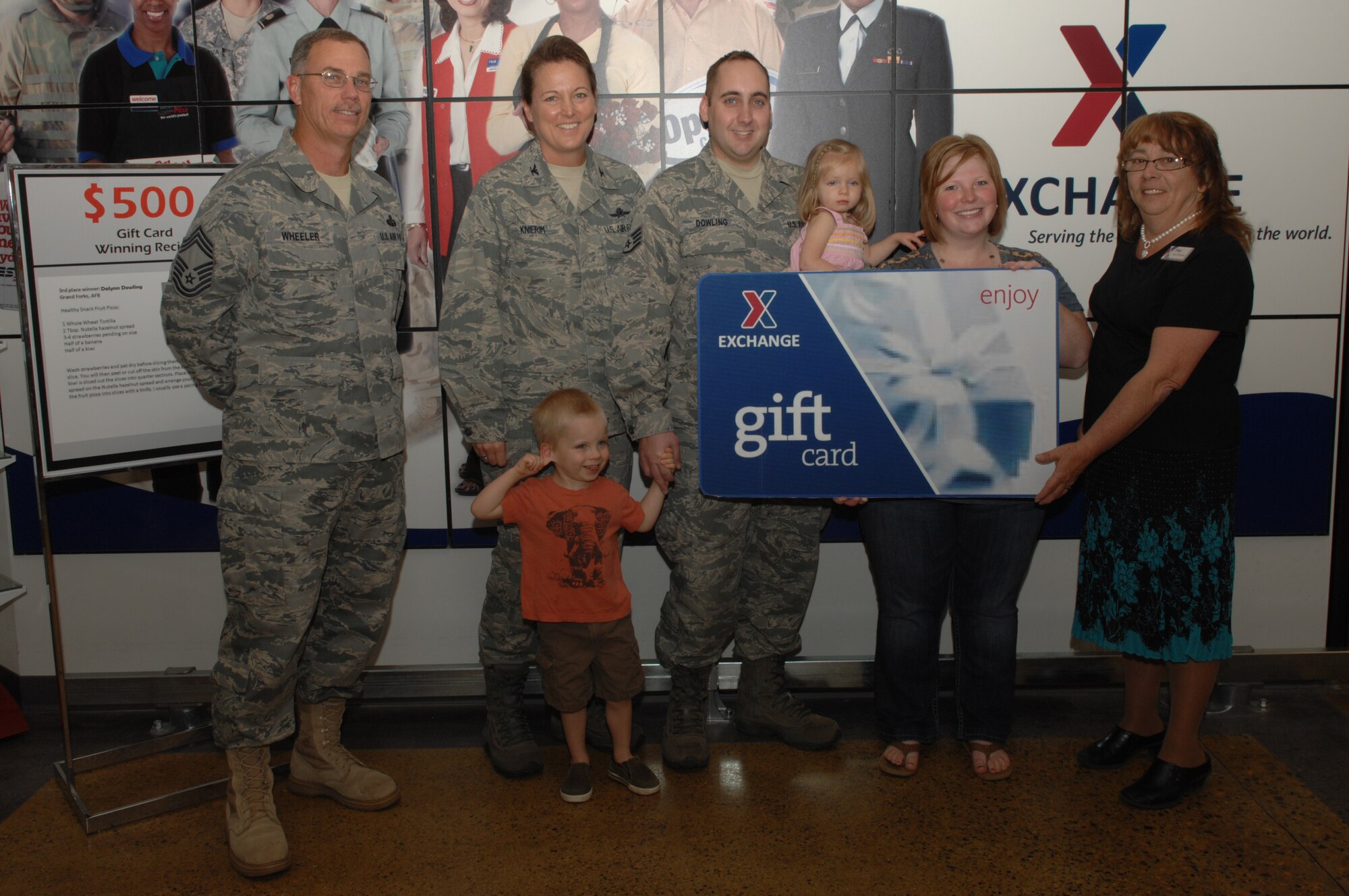 Pat Fields, manager of the Grand Forks Army & Air Force Exchange Service, presents a gift card to Dalynn Dowling, wife of Staff Sgt. William Dowling, 319th Communications Squadron, accompanied by Col. Tammy Knierim, 319th Mission Support Group commander and Chief Master Sgt. Robert Wheeler, 319th MSG, for placing third in the healthy recipe contest on Grand Forks Air Force Base Oct.  5. Mrs. Dowling received a $500 gift card for her healthy snack fruit pizza recipe.  (U.S. Air Force photo by Airman 1st Class Ashley N. Taylor)
