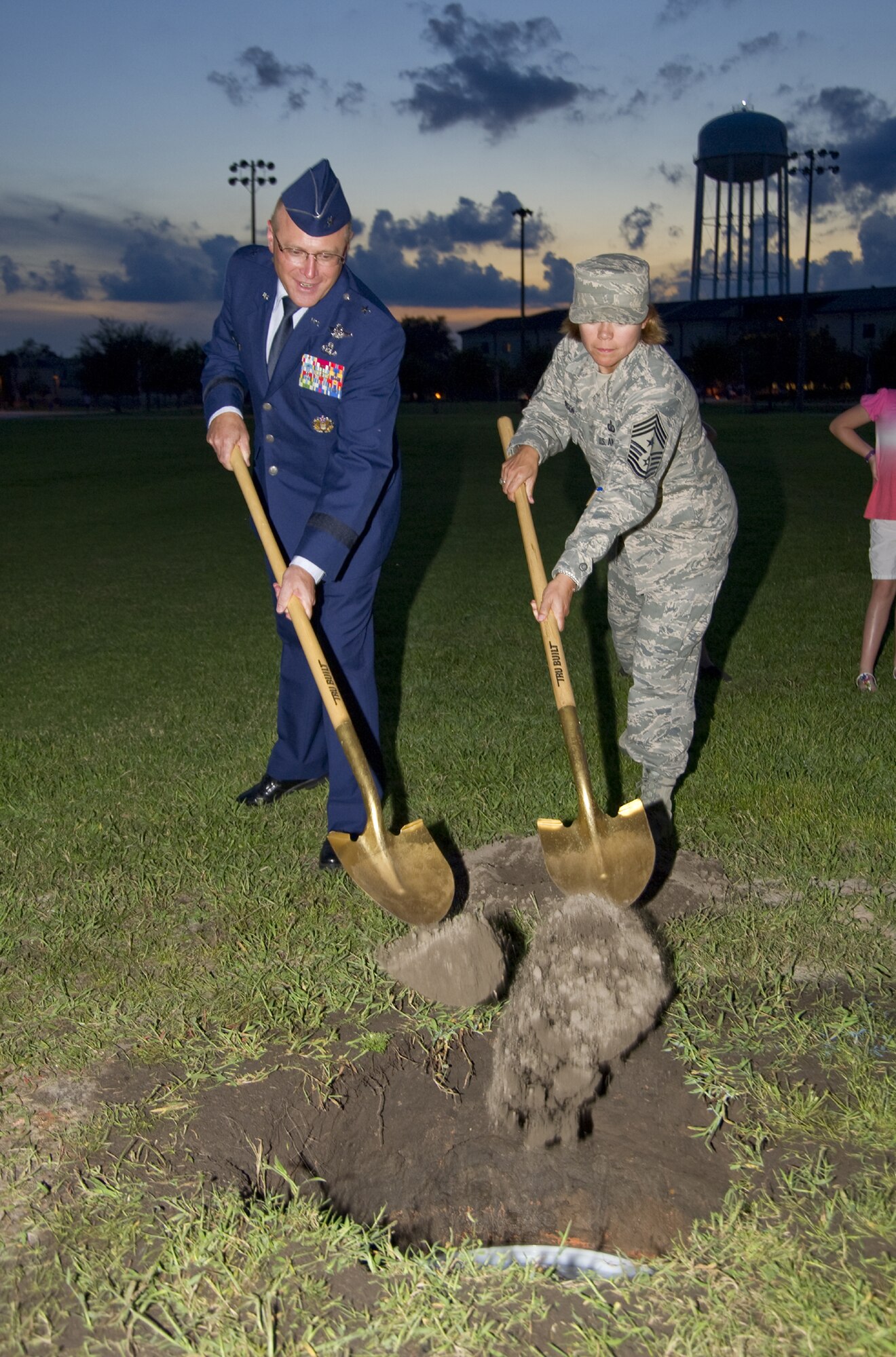 Brig. Gen. Andrew Mueller, 81st Training Wing commander, left, and Chief Master Sgt. Angelica Johnson, 81st TRW command chief, shovel dirt over the time capsule
buried on the parade field Sept. 29, to commemorate Keesler’s 70th birthday earlier this year.  (U.S. Air Force photo by Adam Bond)