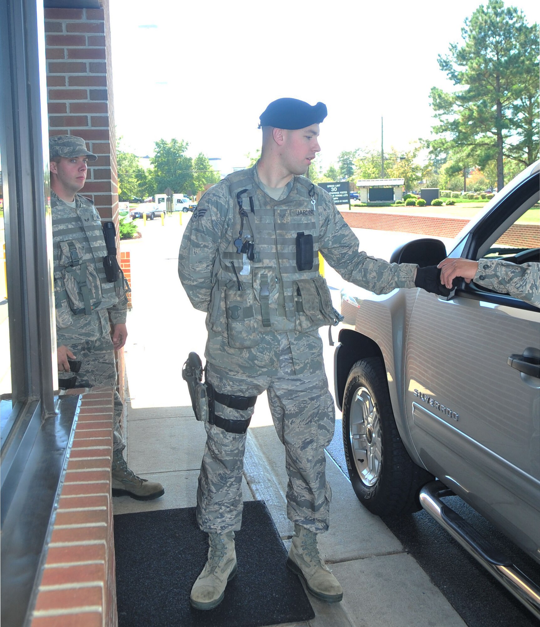 Senior Airman Stephen Jardine checks the ID of an Airman requesting permission to enter Seymour Johnson Air Force Base, N.C., while Senior Airman Michael Worley, a 4th Security Forces Squadron (SFS) augmentee, watches approaching vehicles, Oct. 4, 2011. Airmen from various career fields are working as security forces augmentees to provide support to the heavily tasked 4 SFS numbers. Jardine is a 4 SFS patrolman from Buffalo, N.Y., and Worley is a 4th Civil Engineer Squadron utilities flight plumber and hails from Asheville, N.C. (U.S. Air Force photo by Senior Airman Marissa Tucker)